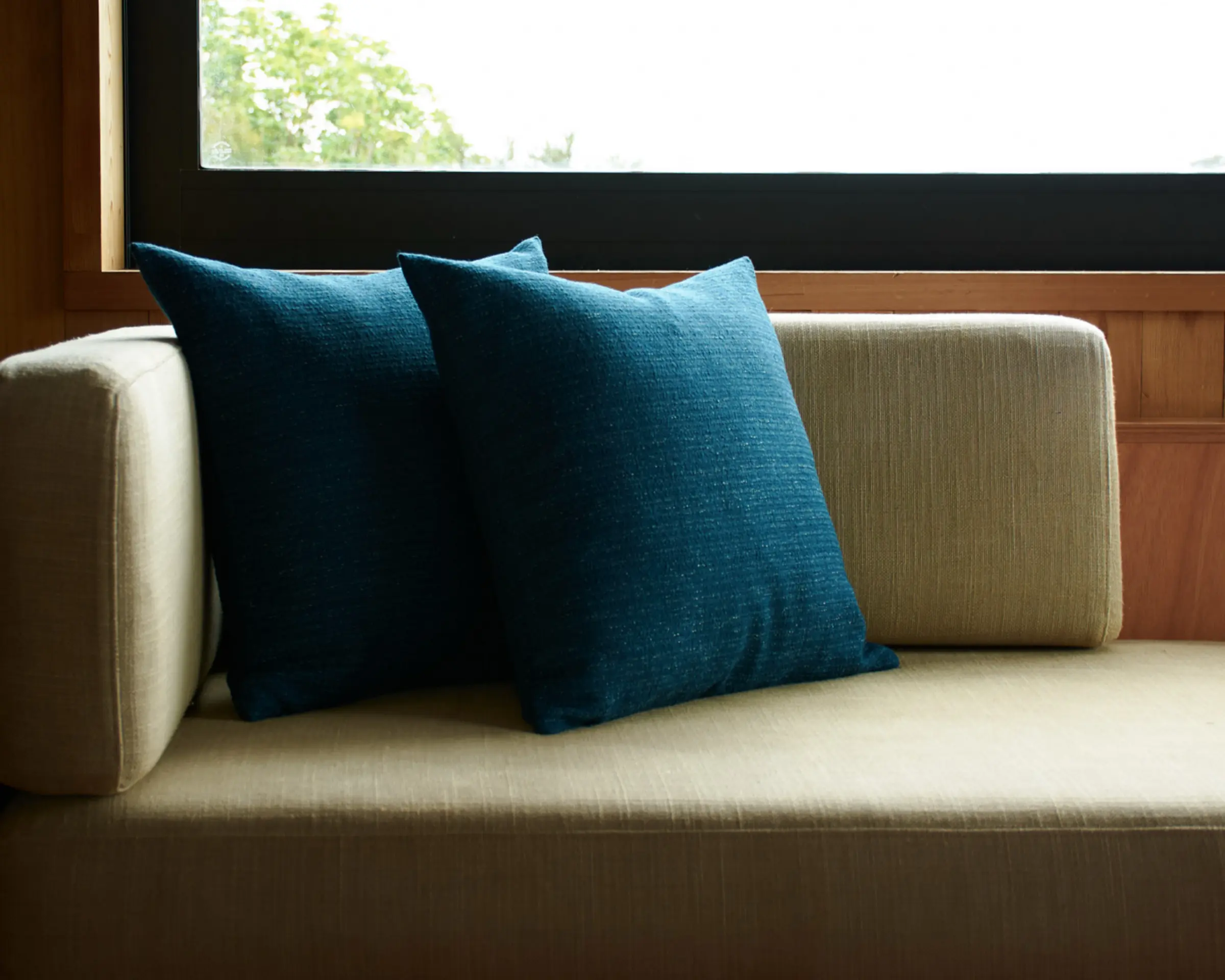 deep teal cushions on an inset couch infront of a windowsill
