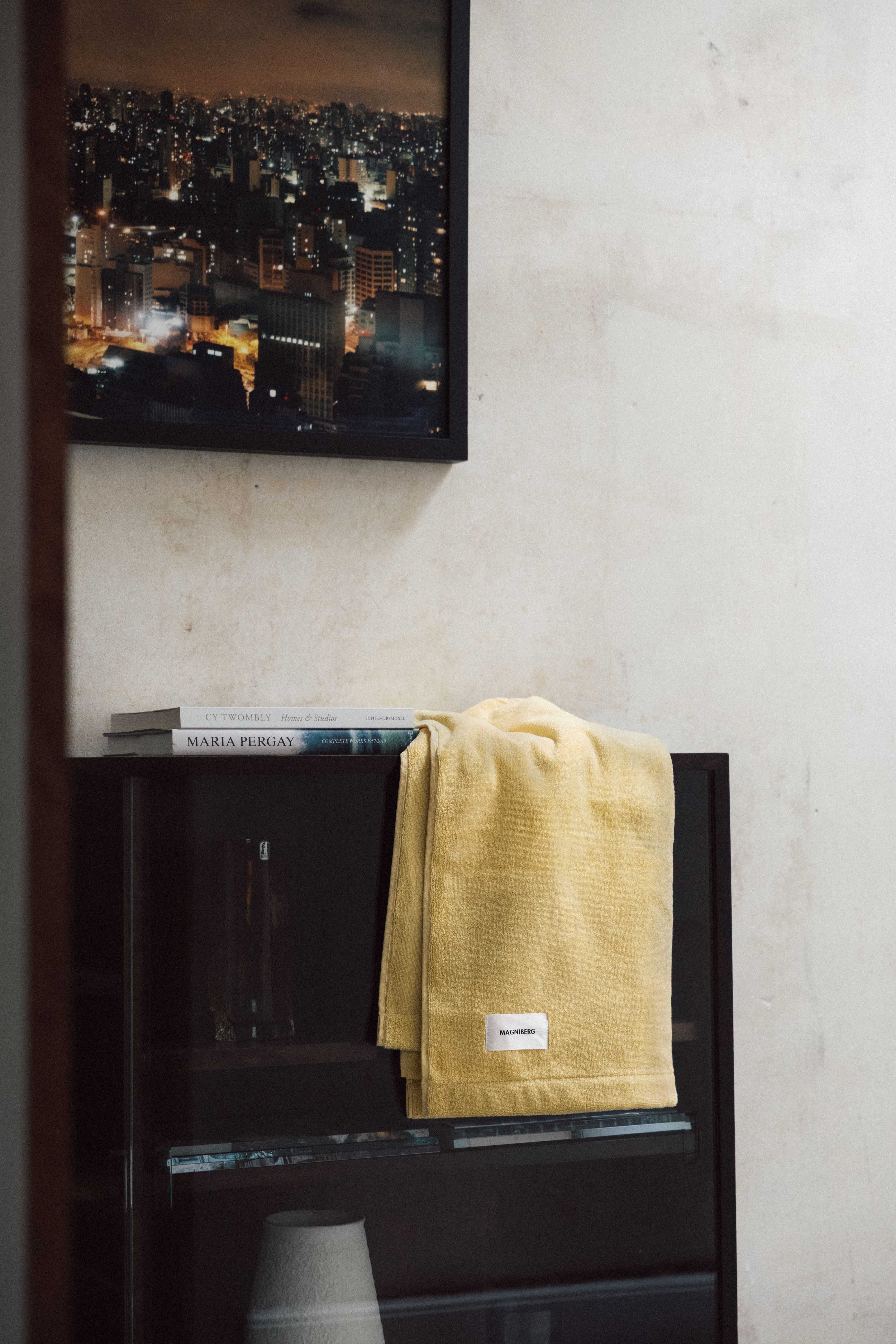 A Magniberg hand towel on a black side unit with a picture above it