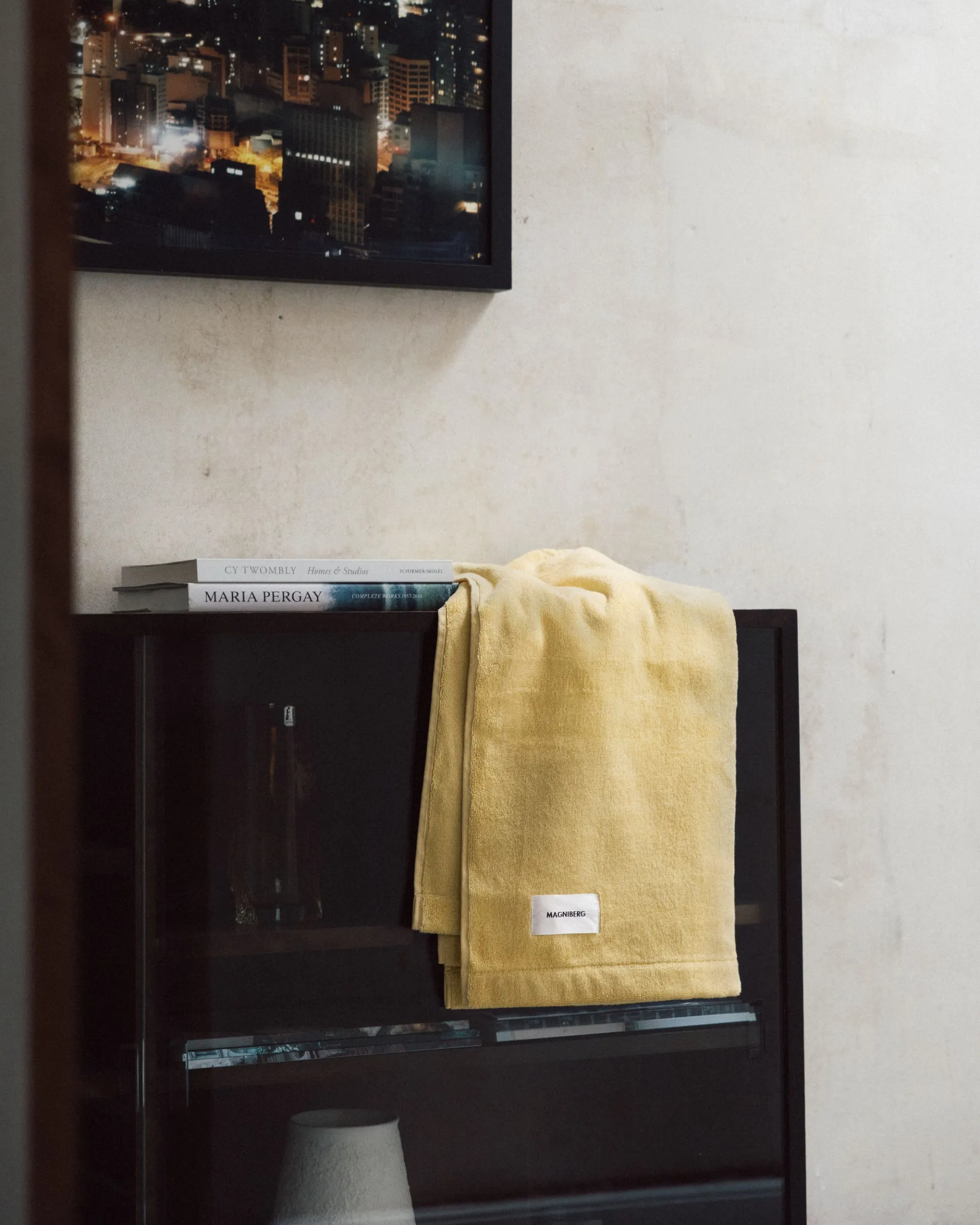 A Magniberg hand towel on a black side unit with a picture above it