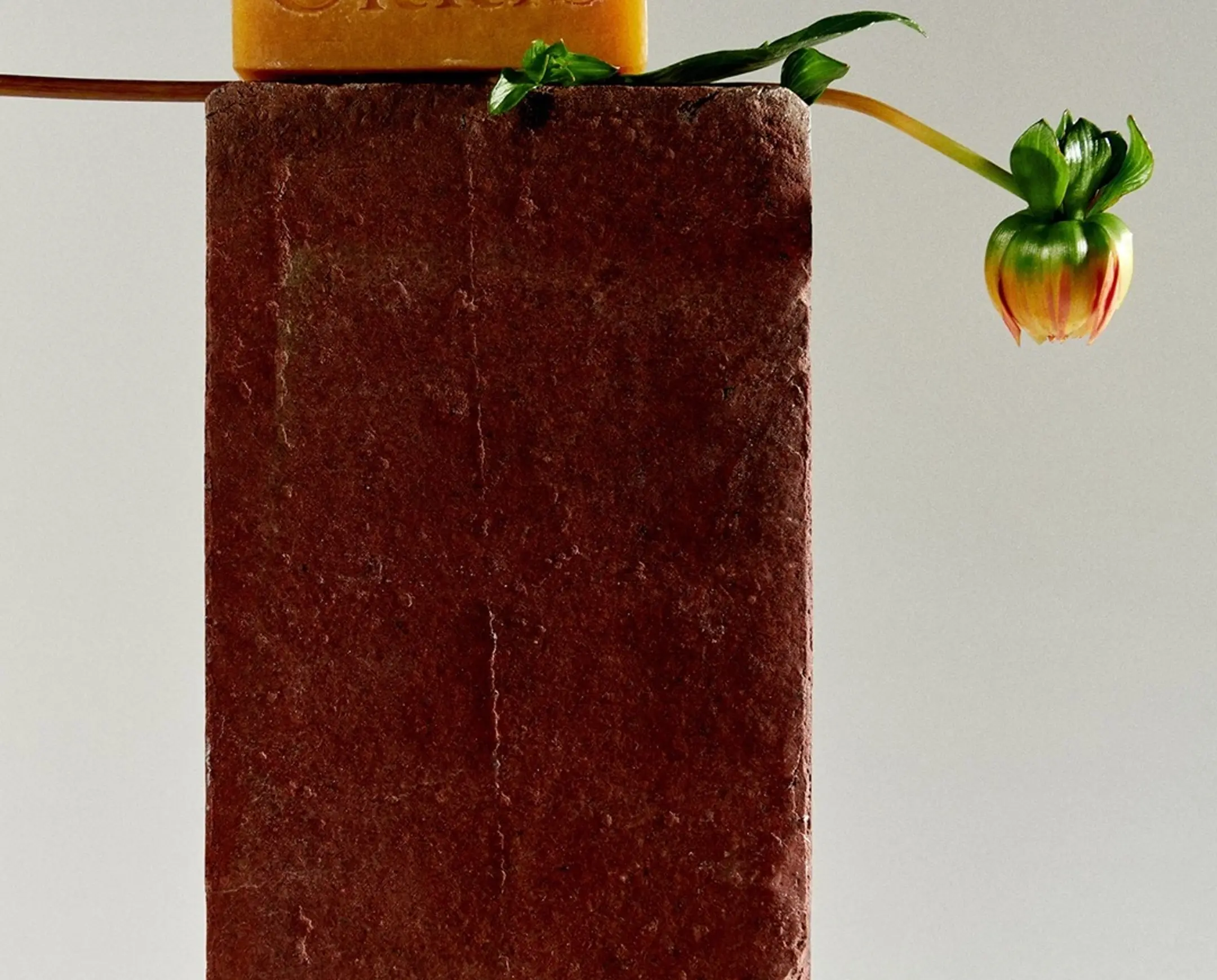 A bar of ORRIS soap on a brick with a flower next to it