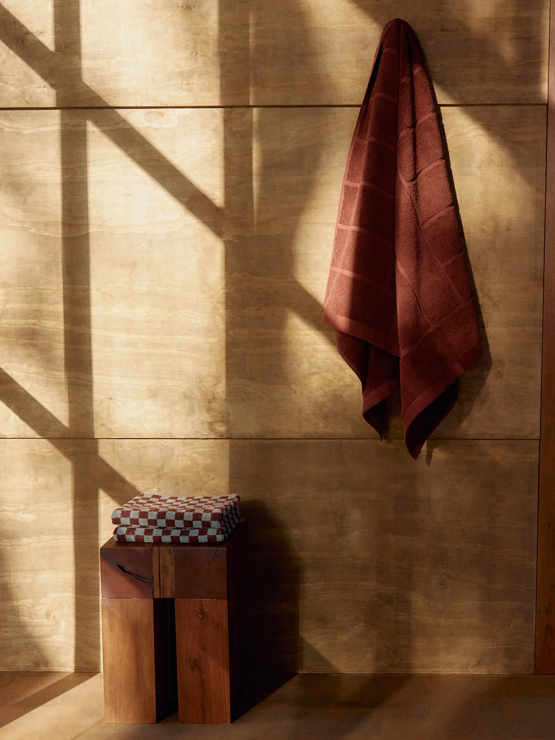 a towel hung on a wood wall with a small square stool next to it