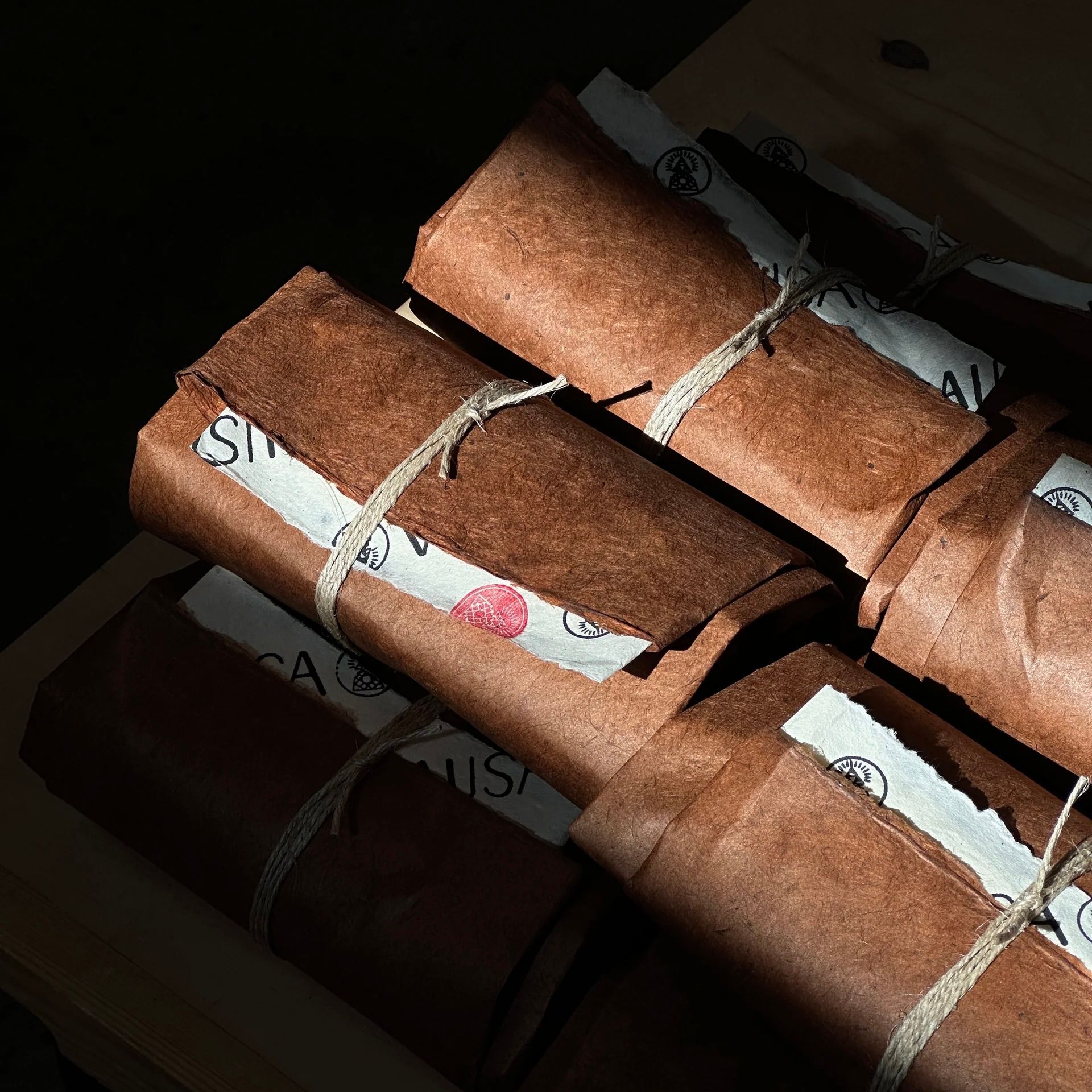 Incausa incense packages, wrapped with string in handmade lokta paper on a black background