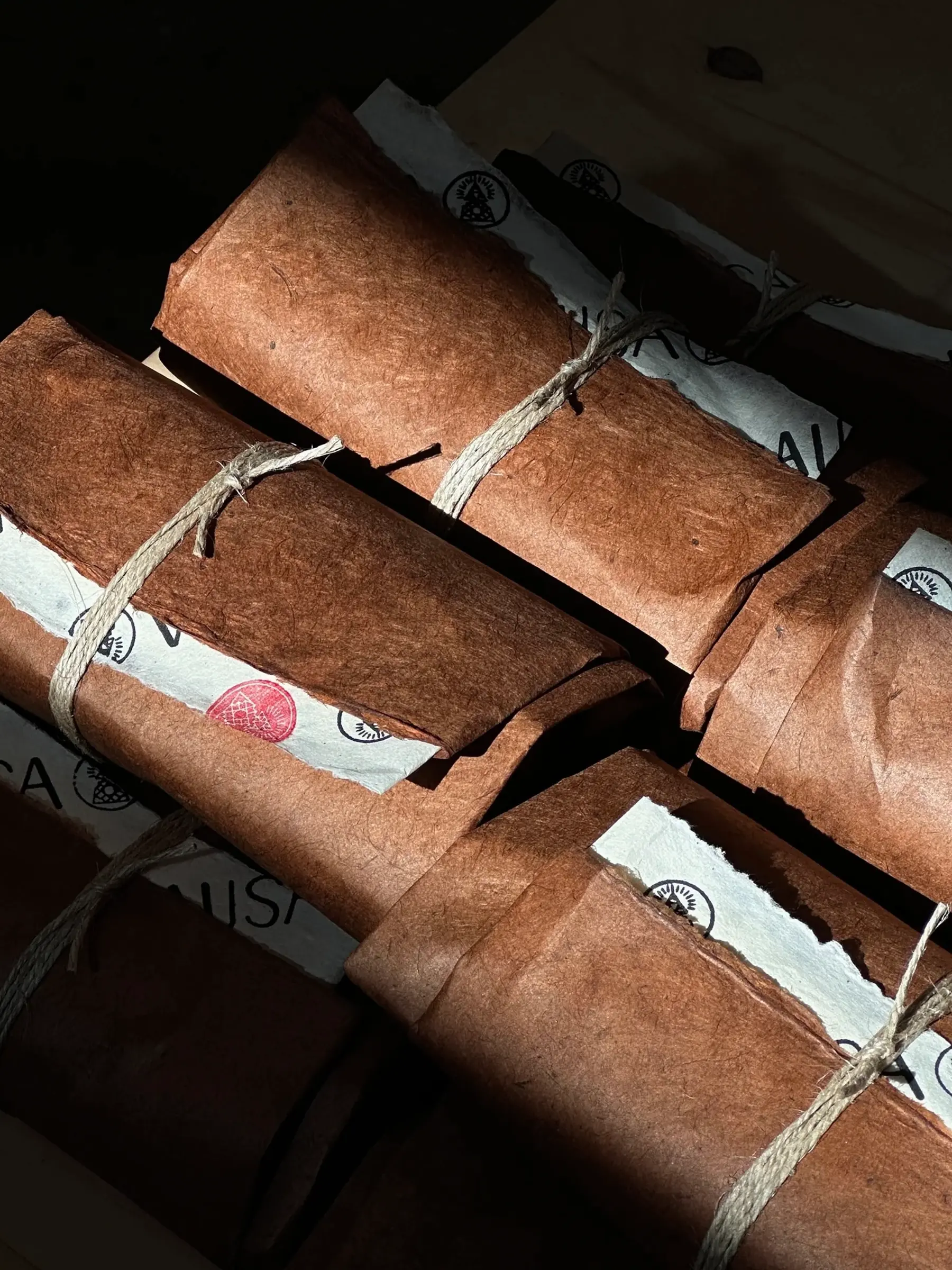 Incausa incense packages, wrapped with string in handmade lokta paper on a black background