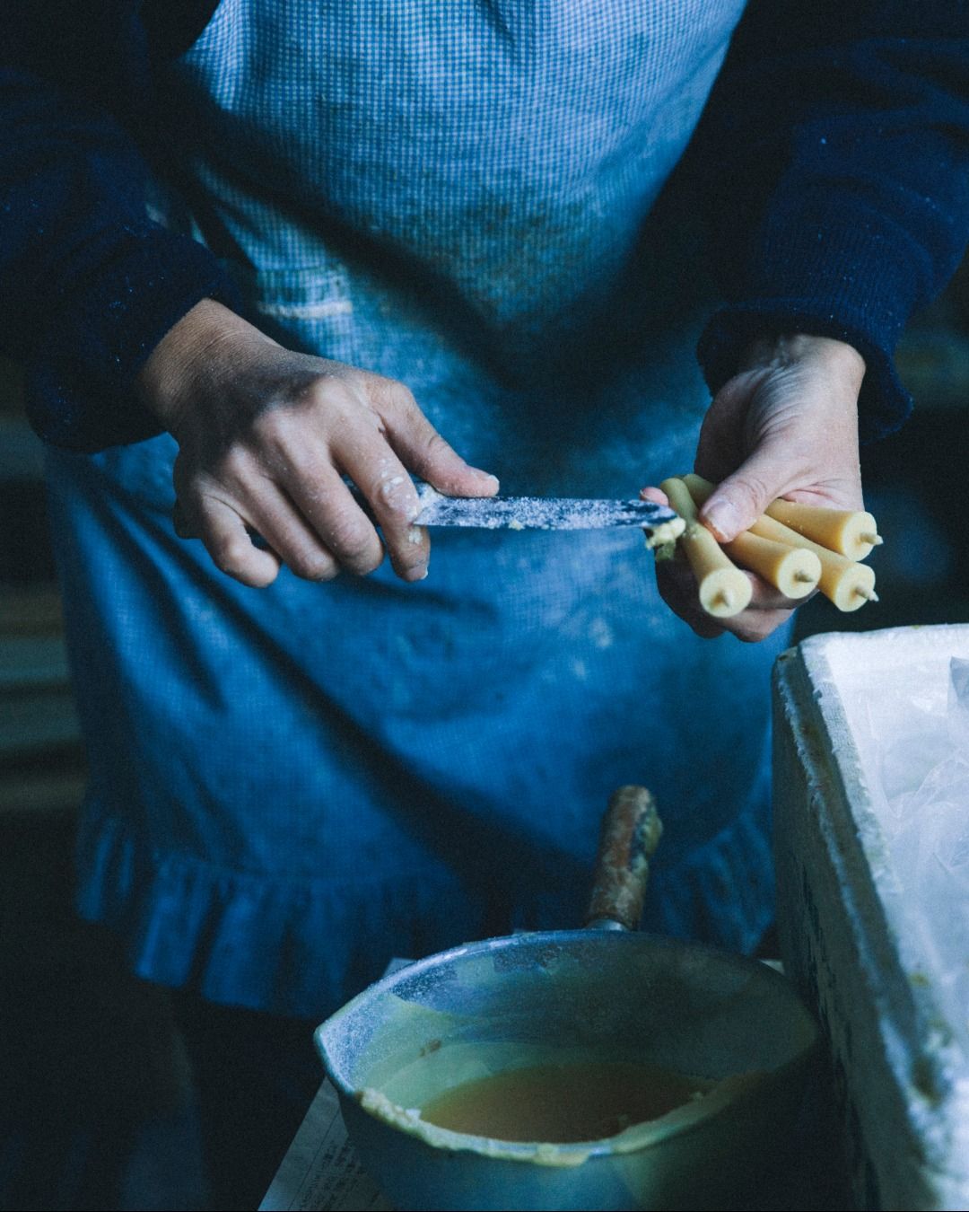 a worker shaving and smoothing the side of candles 