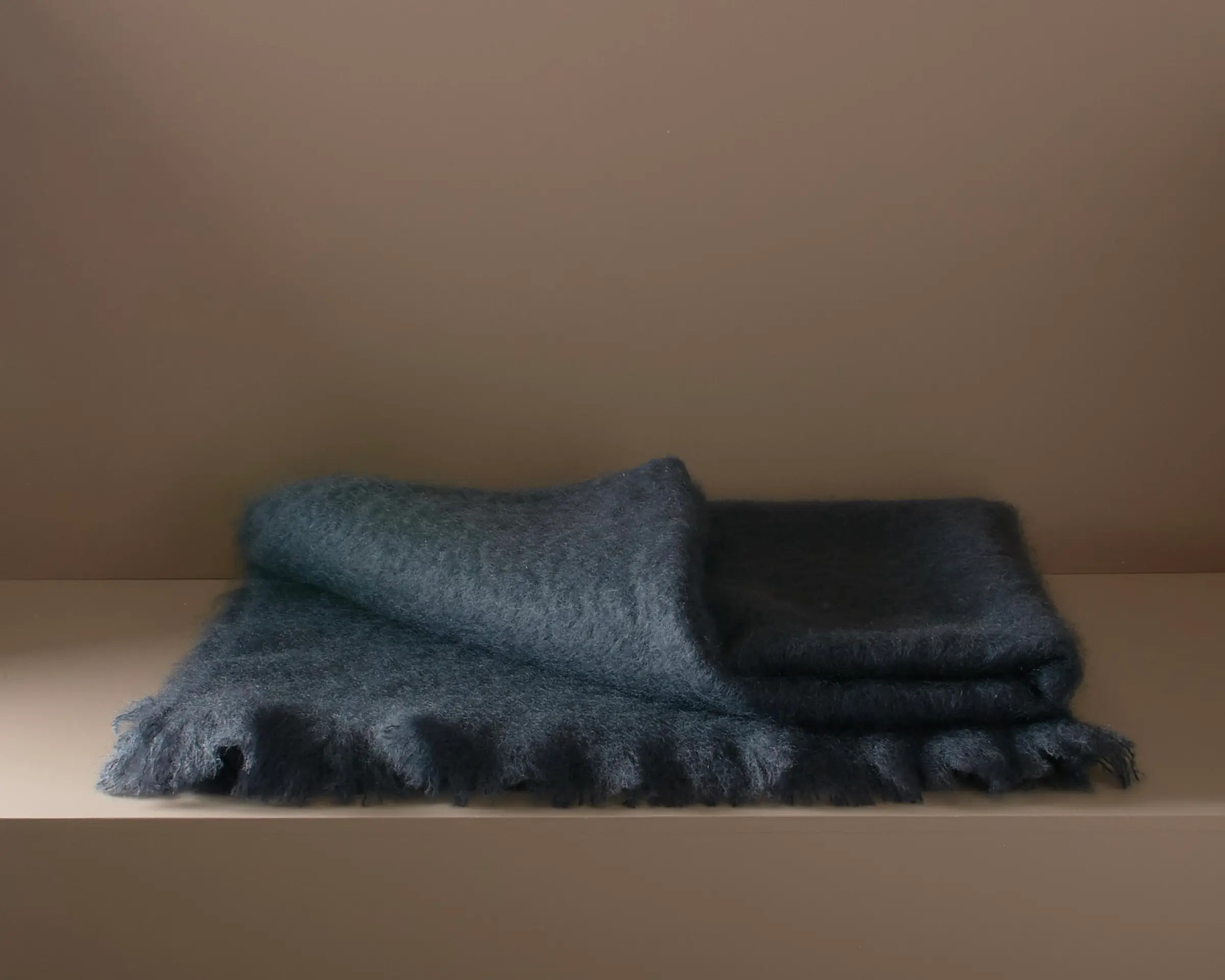 a folded mohair blanket on a plinth