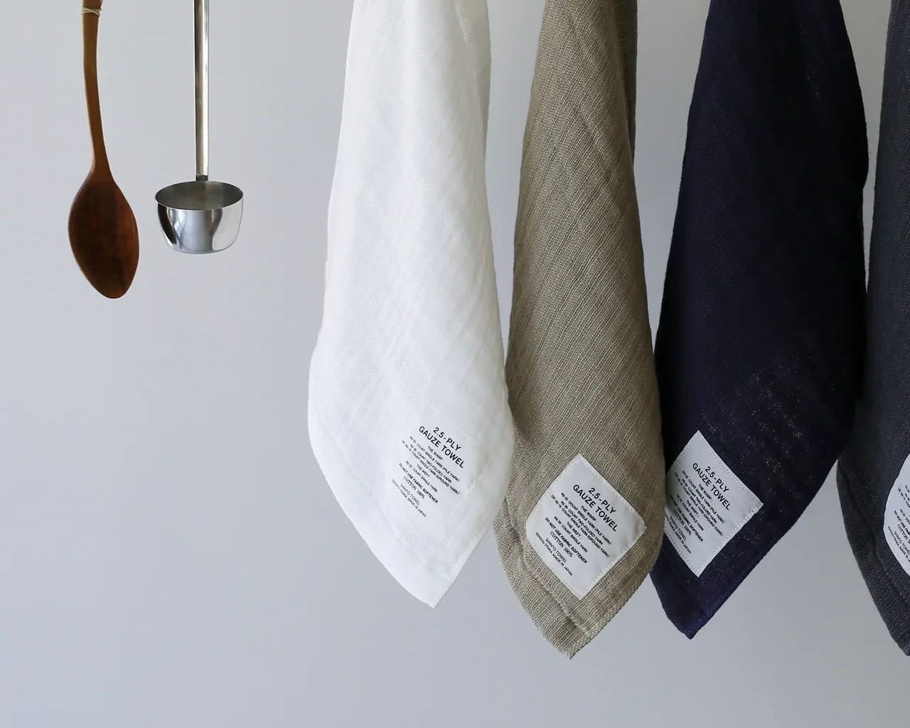 Three Shinto cotton gauze towels hanging on a wooden rail on a white background