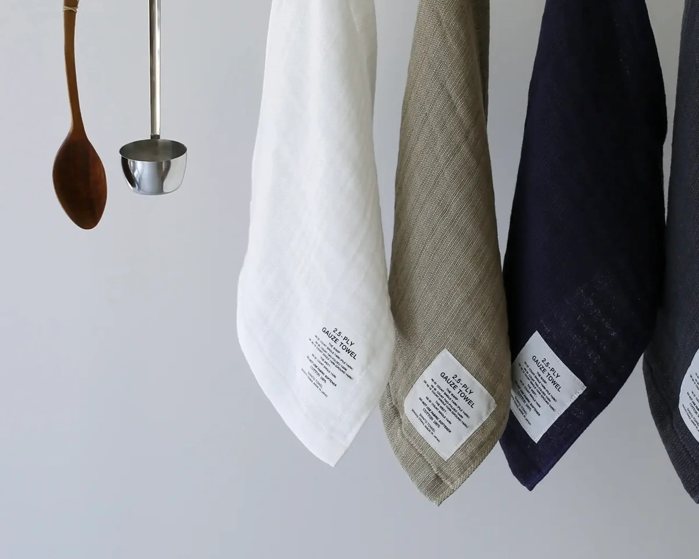 Three Shinto cotton gauze towels hanging on a wooden rail on a white background