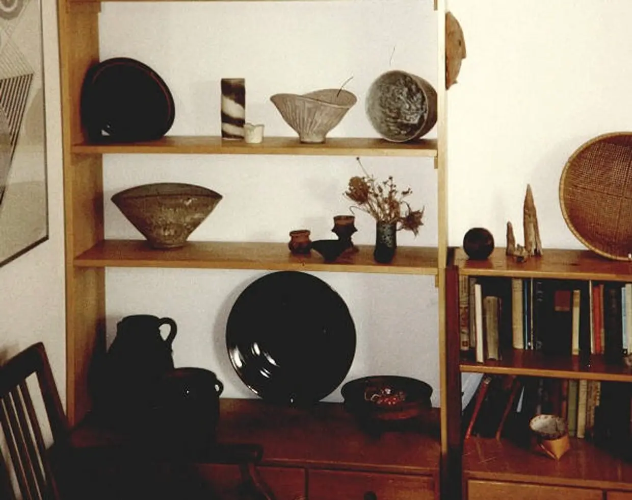 A collection of vintage ceramics and baskets on a shelf in a living room