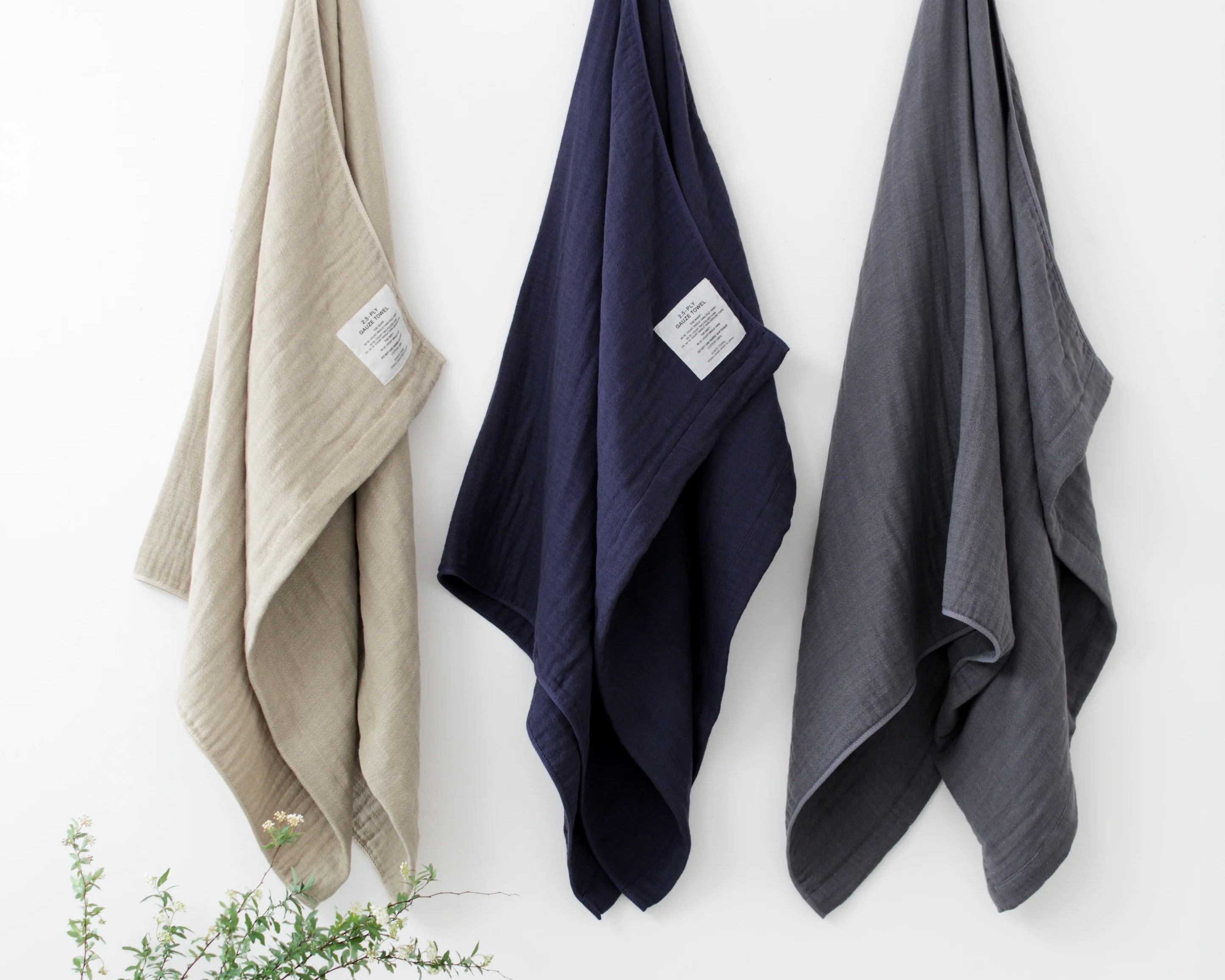 Three Shinto cotton gauze towels hanging on a wooden rail on a white background