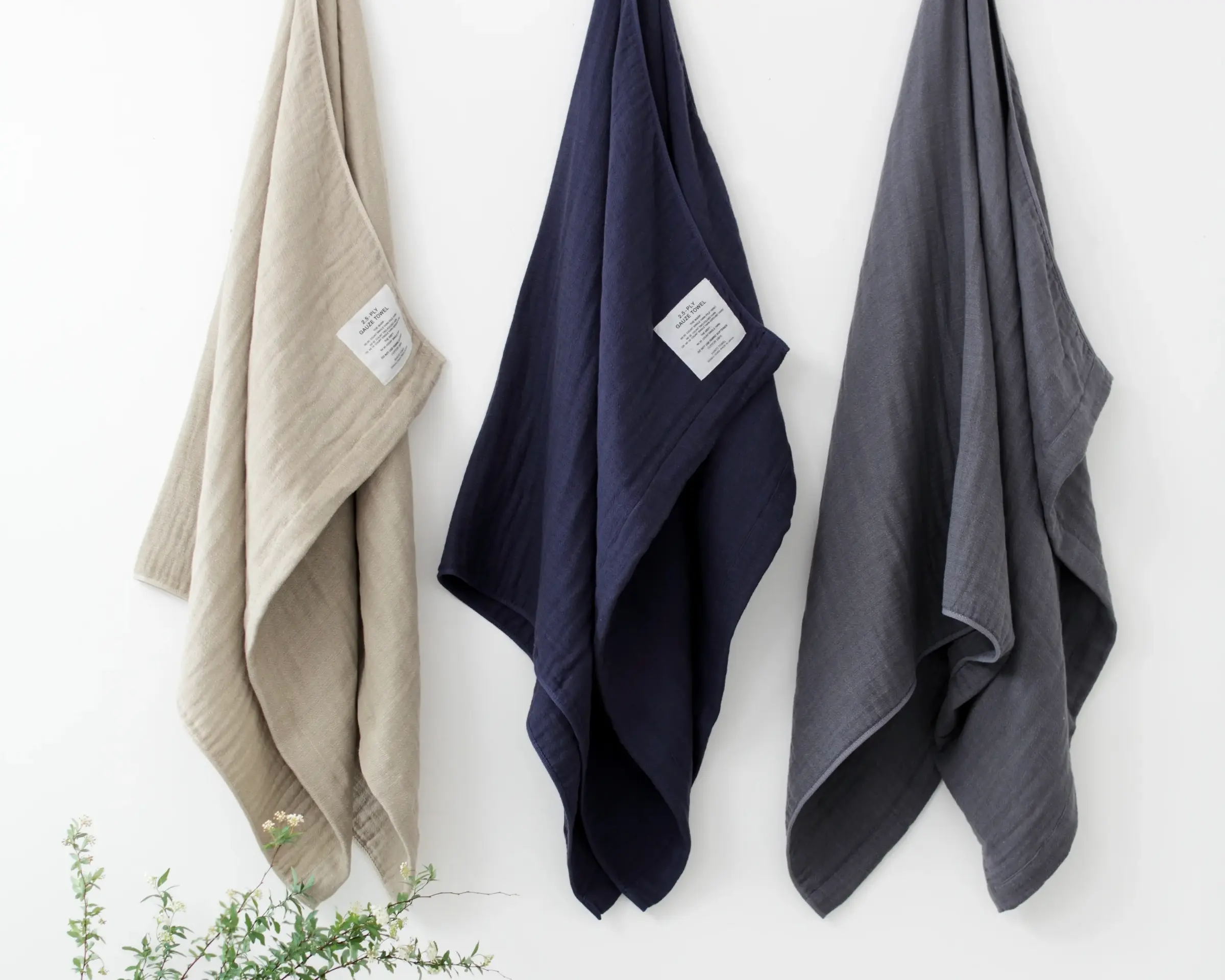 Three Shinto cotton gauze towels hanging on a wooden rail on a white background