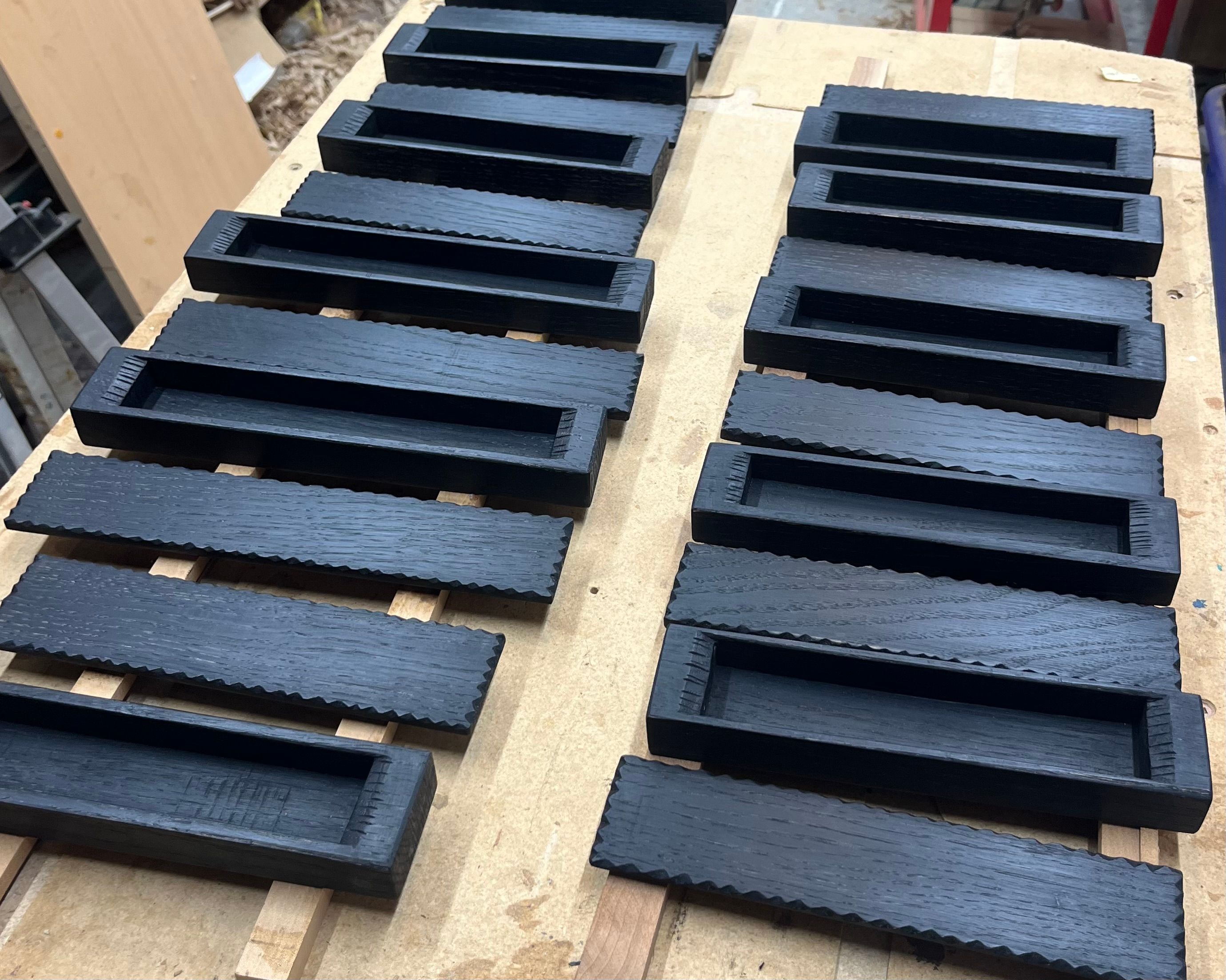 French Oak Band sawn boxes lined up on a work bench with their lids off having just been ebonised. 