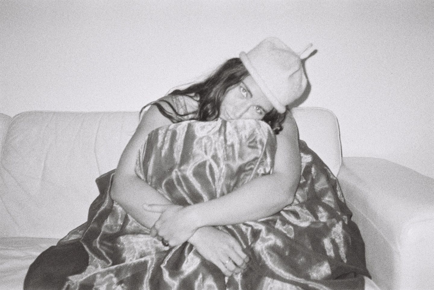A photo shoot of a woman wearing a bonnie Wroe possum merino hat, hand knitted in New Zealand. Laying on a white couch