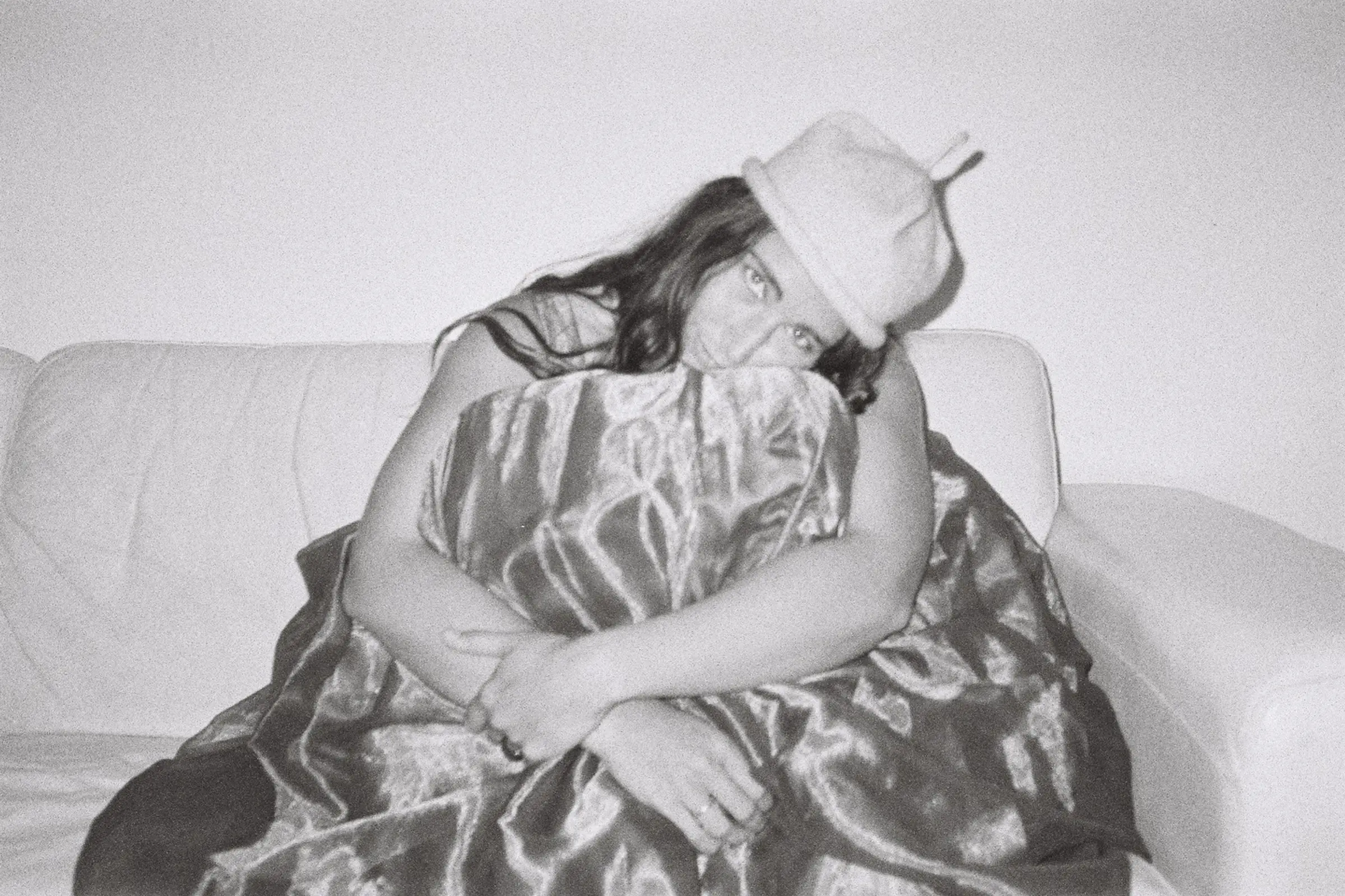A photo shoot of a woman wearing a bonnie Wroe possum merino hat, hand knitted in New Zealand. Laying on a white couch