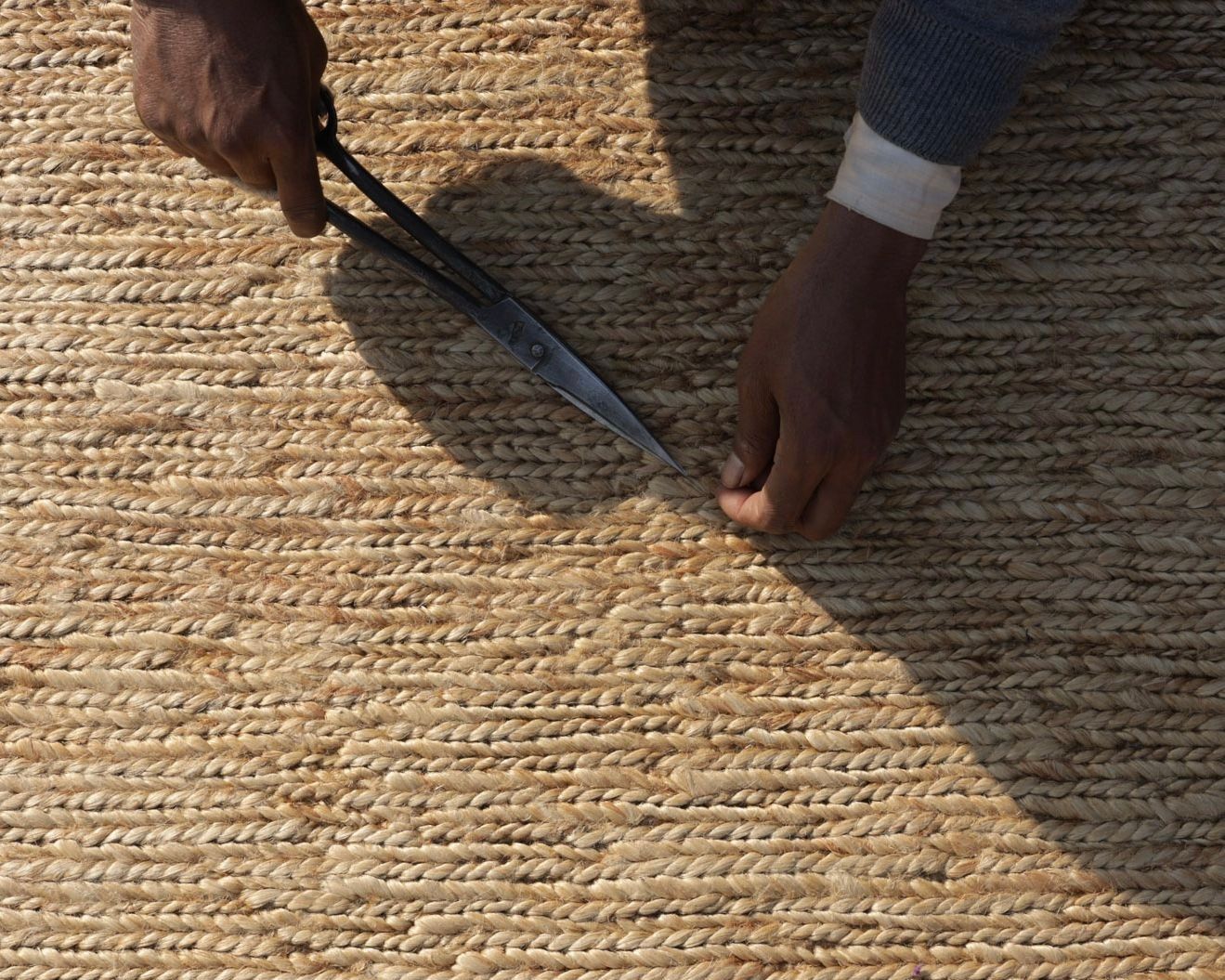A braided jute mat being hand finished 