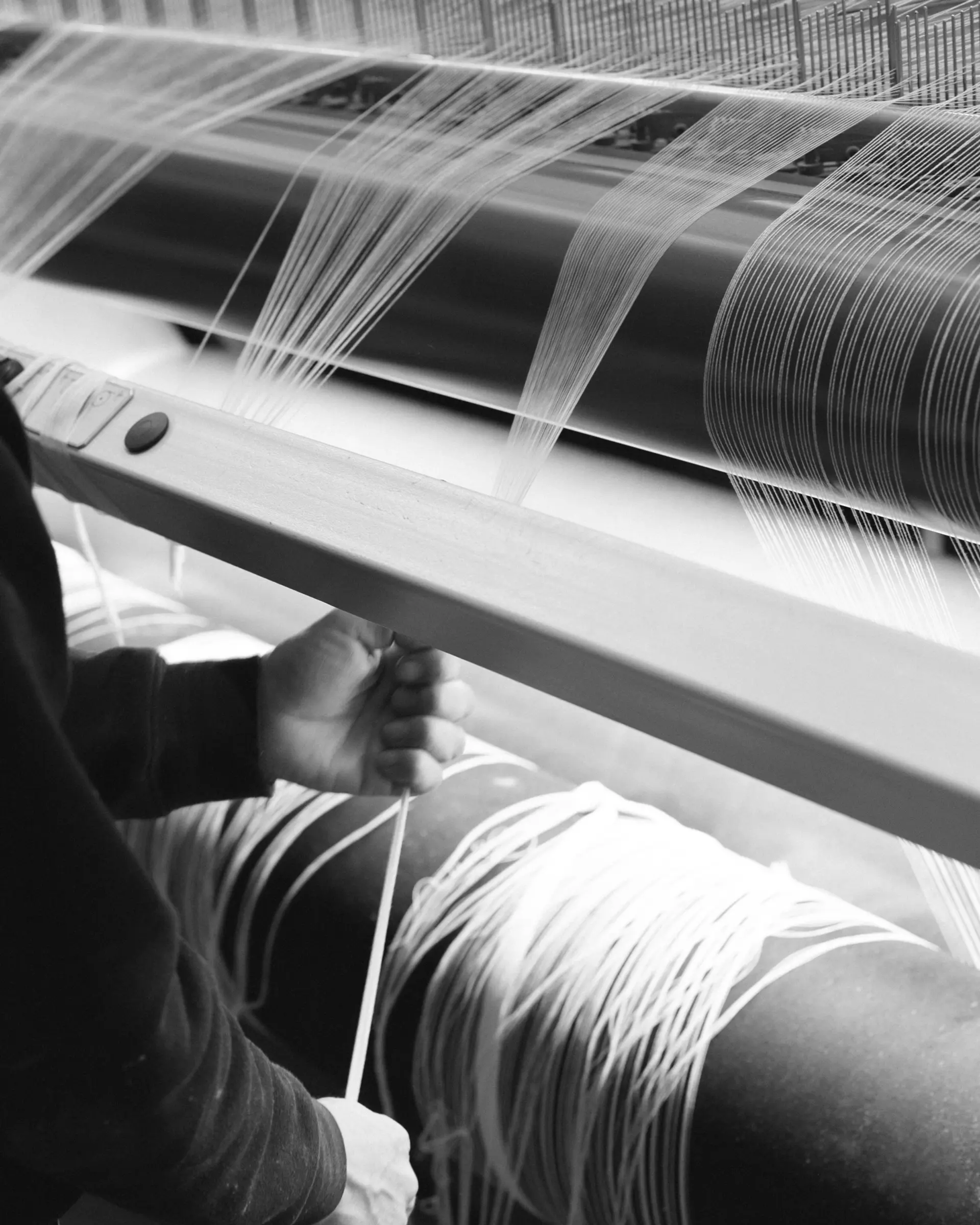 A loom machine weaving towels, a worker pulling the fibres through