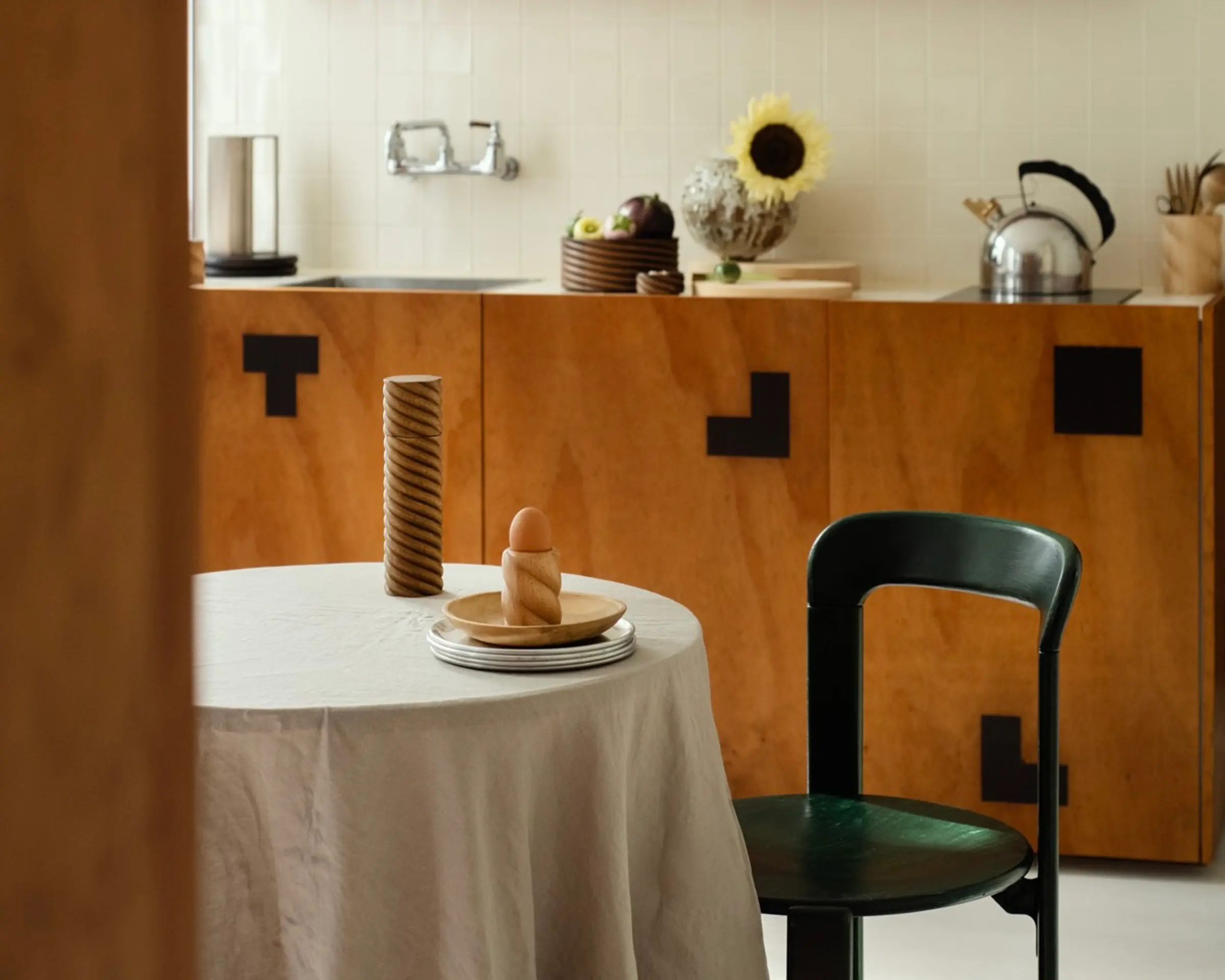 OROS Torsade rosewood egg cup and turned wood pepper mill on a dining table, showcasing the sculptural spiral forms inspired by 17th-century furniture.
