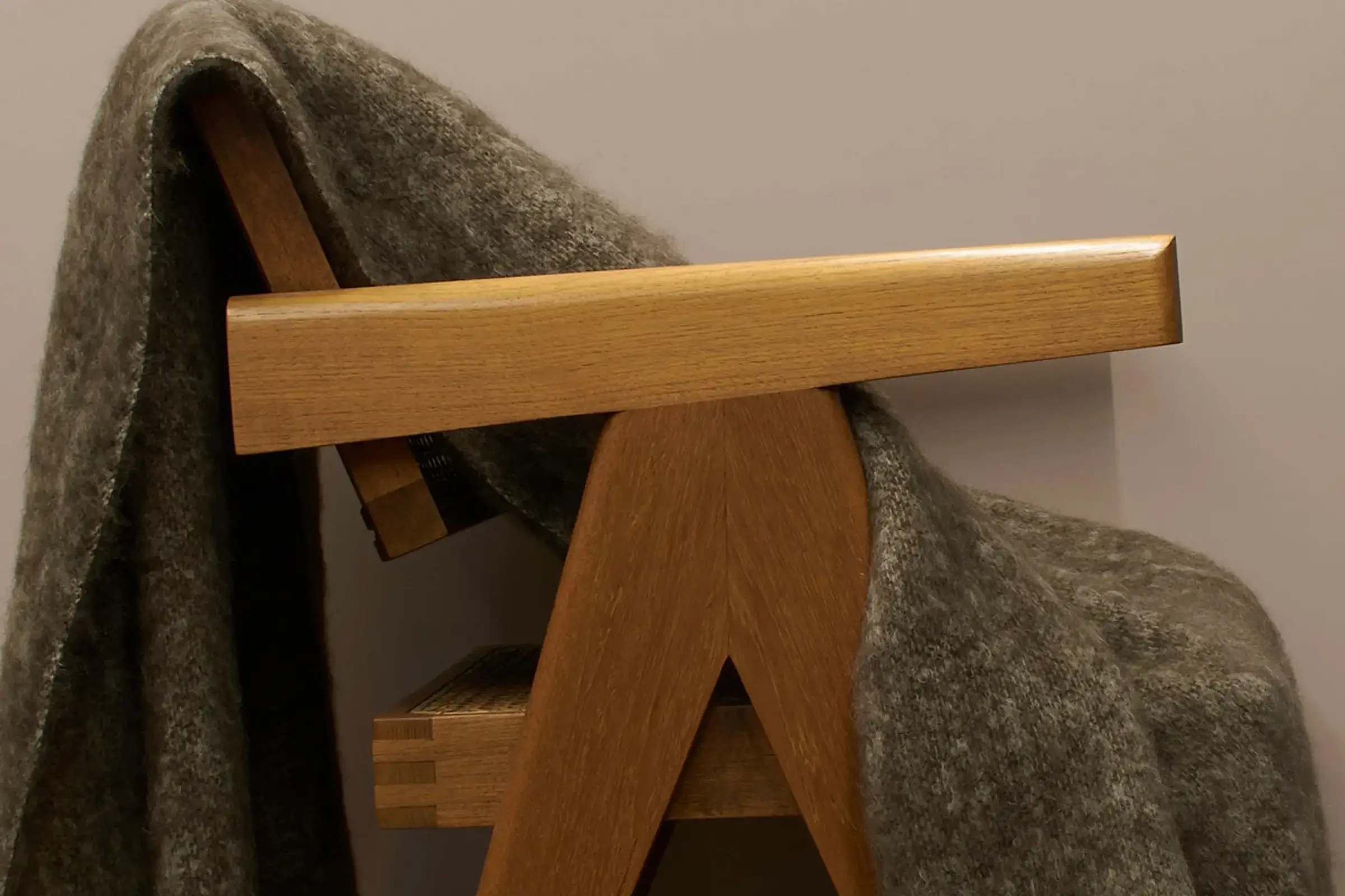 The masterweave kiwi coloured mohair blanket sitting on a Phantom hands office chair v-leg wooden chair with a beige background
