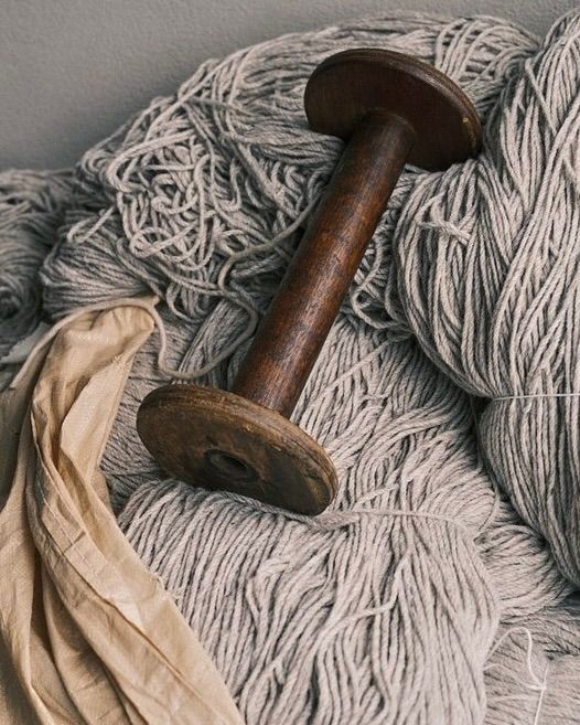 A vintage wooden bobbin in a stack of wool yarn