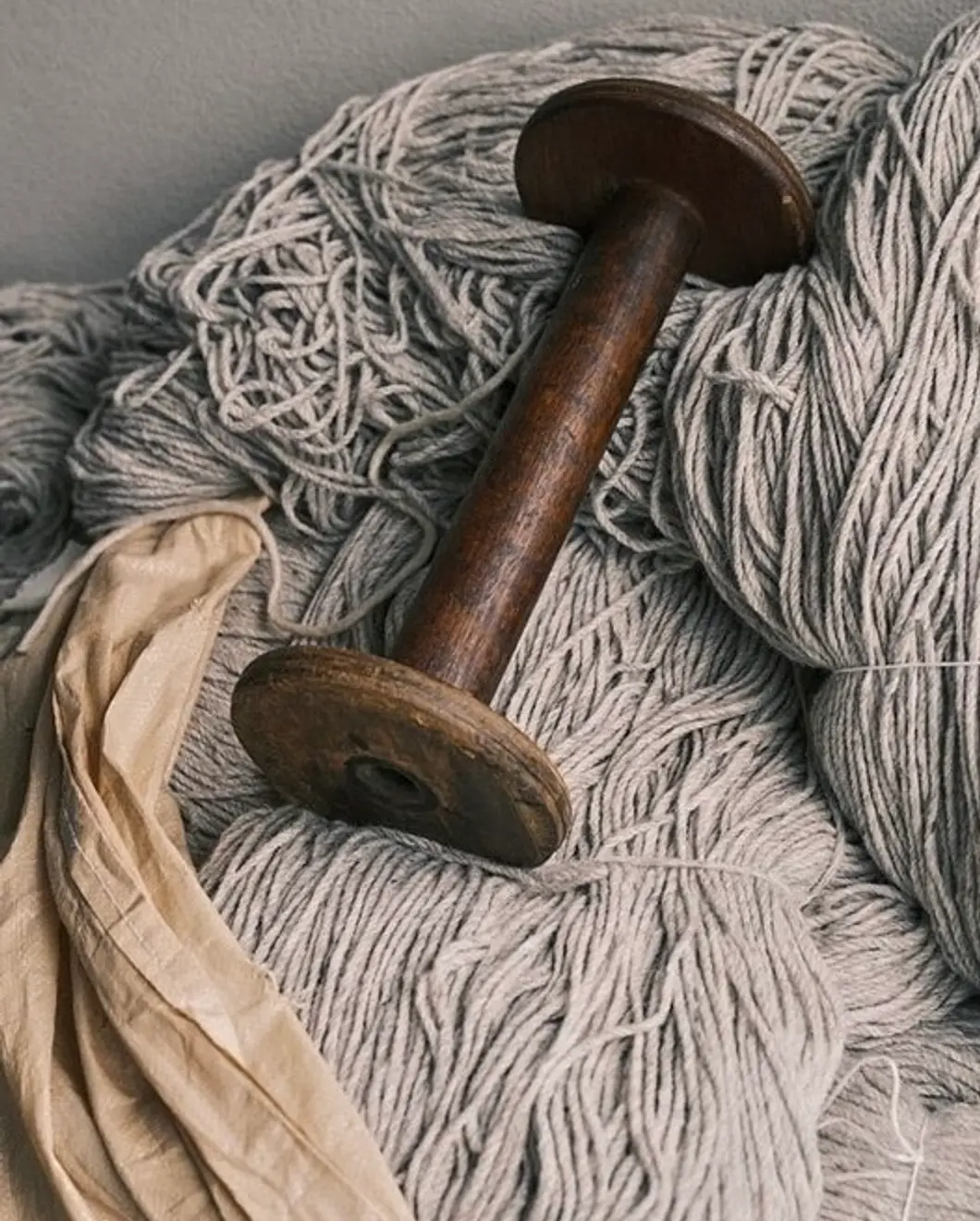 A vintage wooden bobbin in a stack of wool yarn