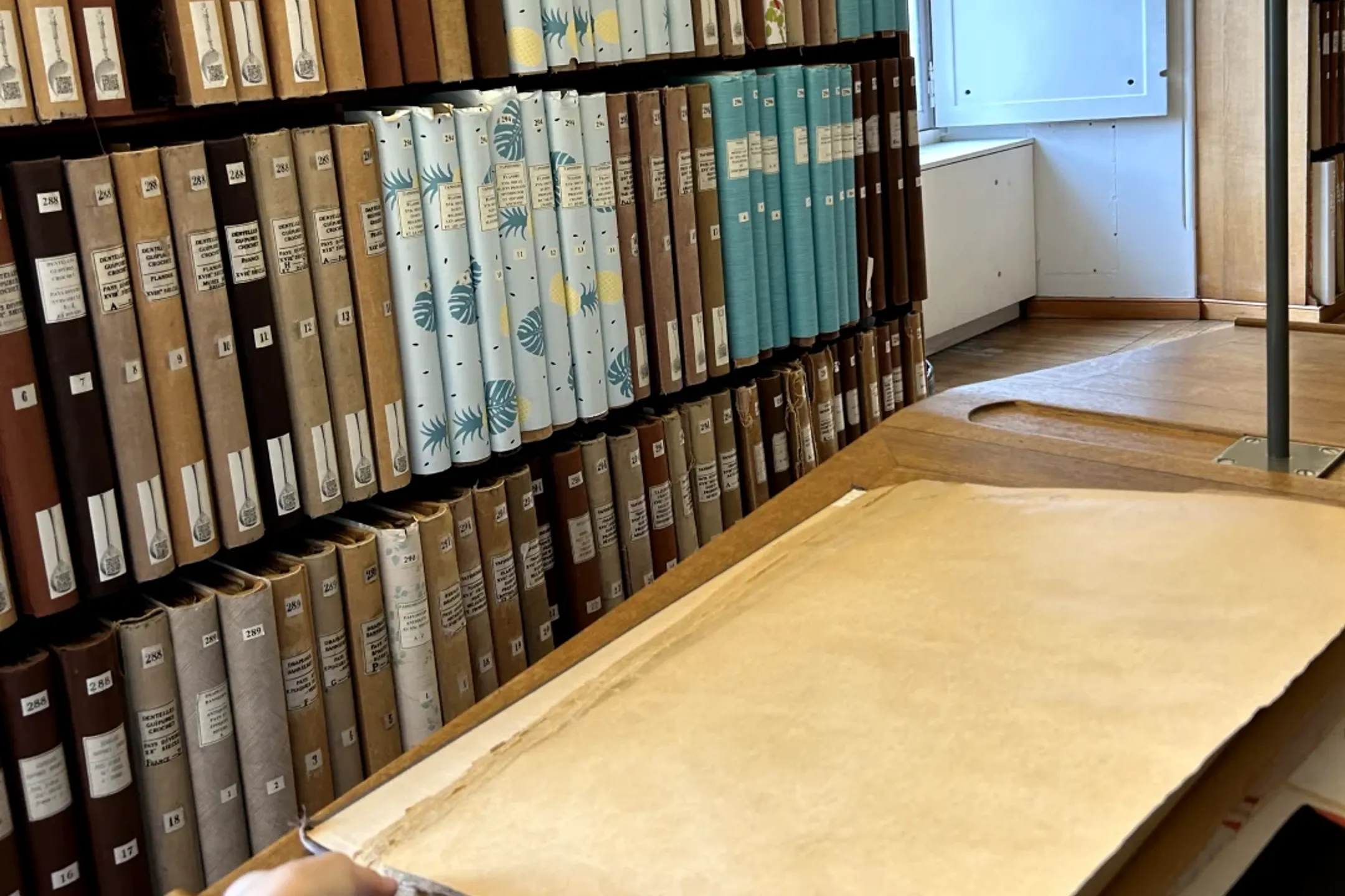 archival books in a bookshelf filled with antique jacquard samples and prints