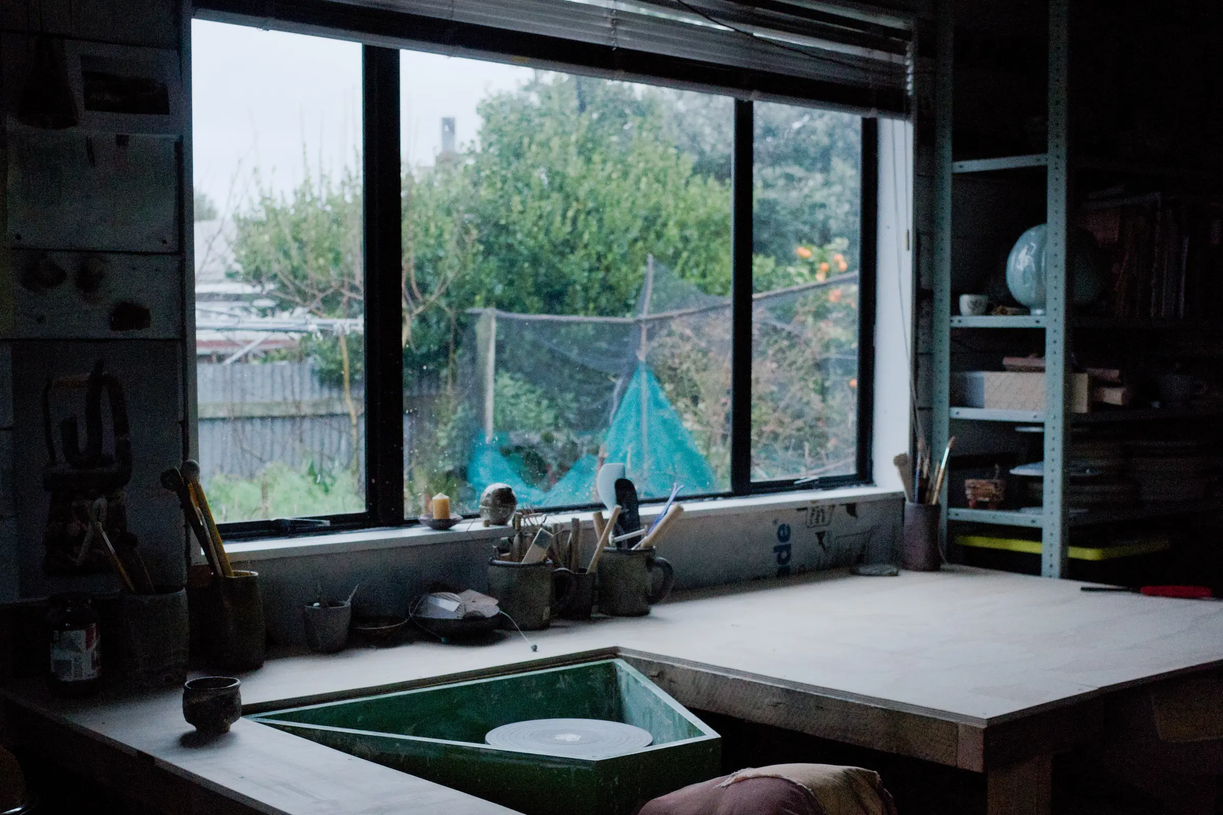 image of a potters workspace with a throwing wheel infront of a window