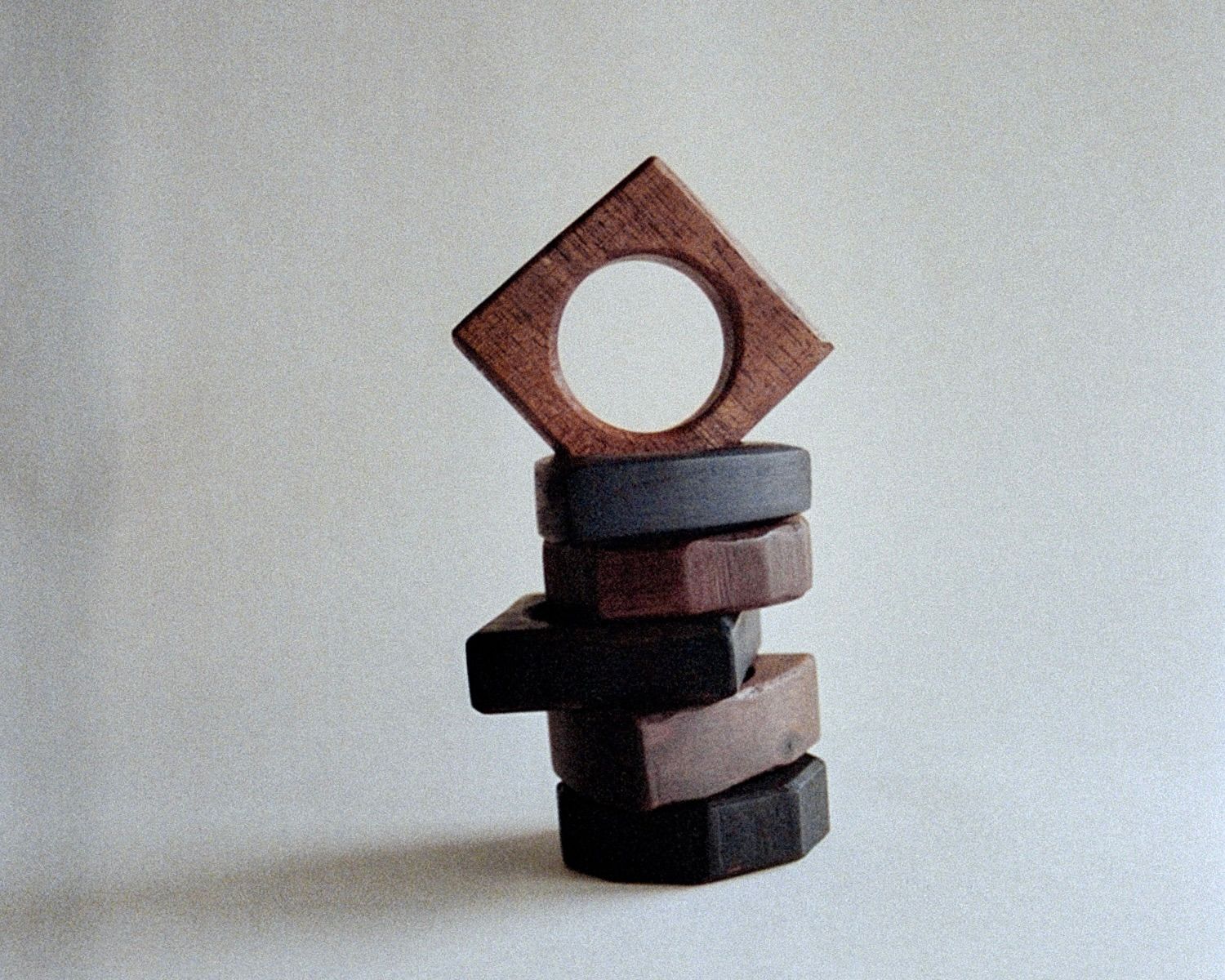 A stack of handmade wooden napkin rings by Josephine Jelicich on a cream background, shot on film