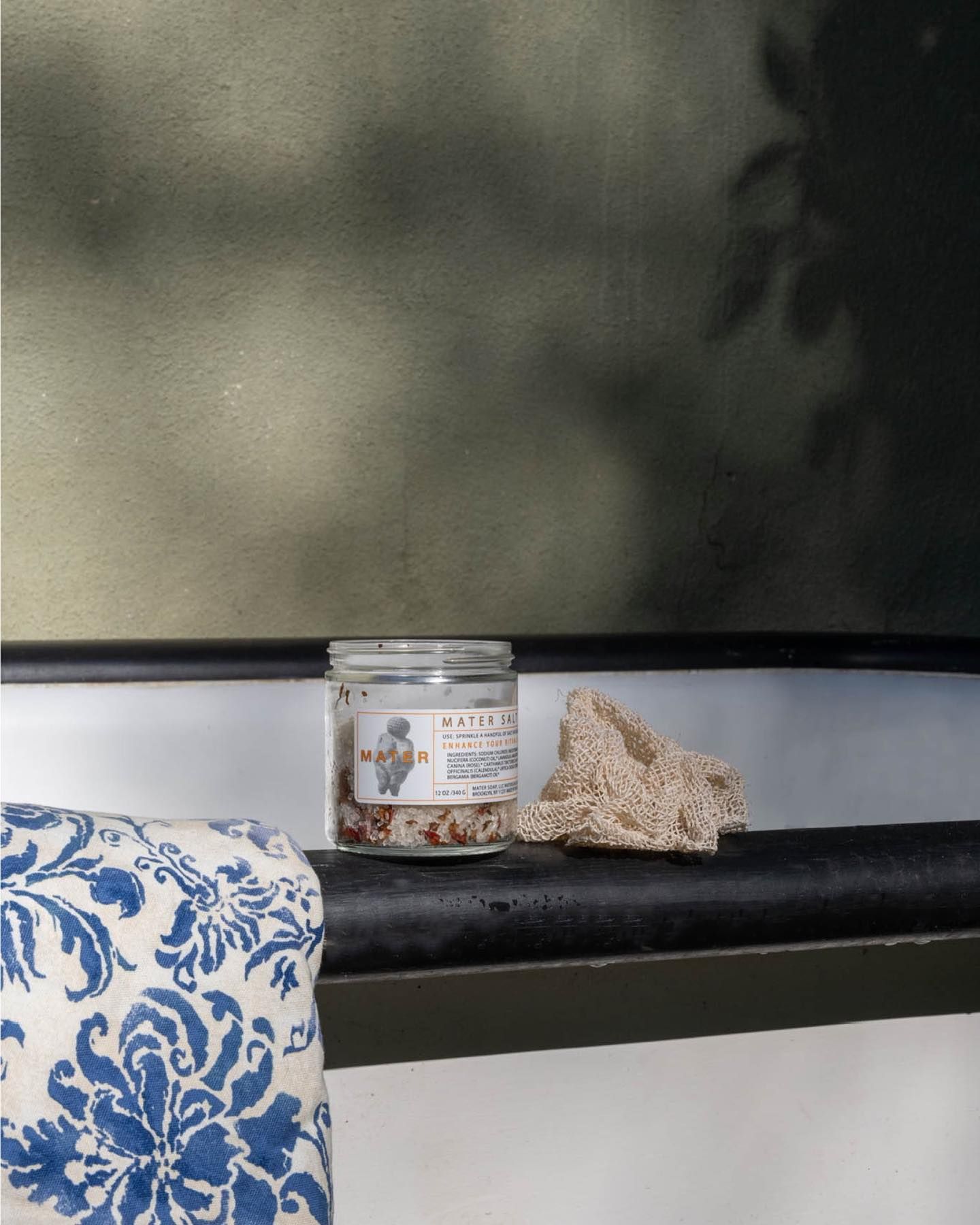 Mater Salt soak and Agave Sponge with a blue and white towel photographed in an outside bath setting