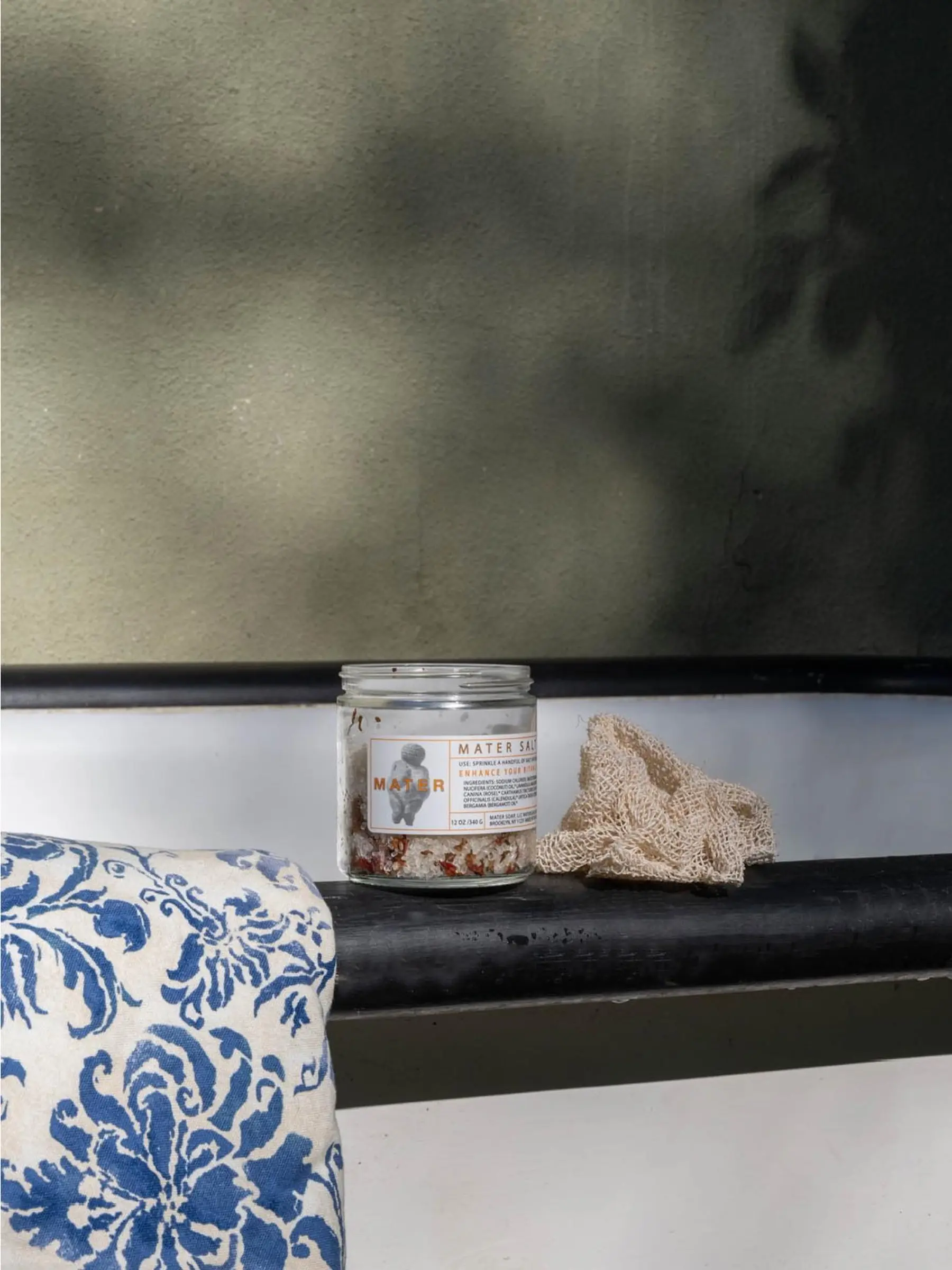 Mater Salt soak and Agave Sponge with a blue and white towel photographed in an outside bath setting