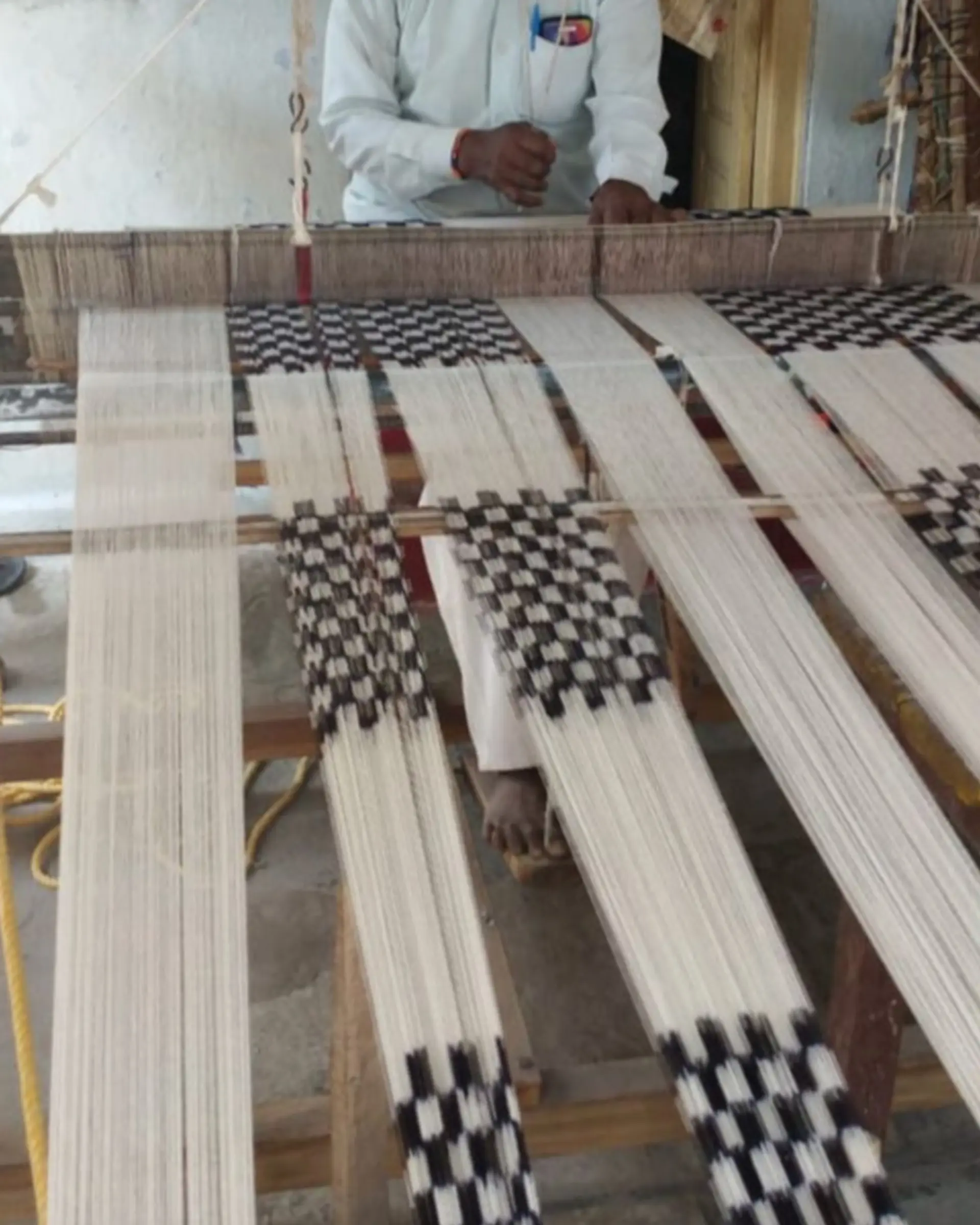 fibre on a loom being woven into a checker print tea towel