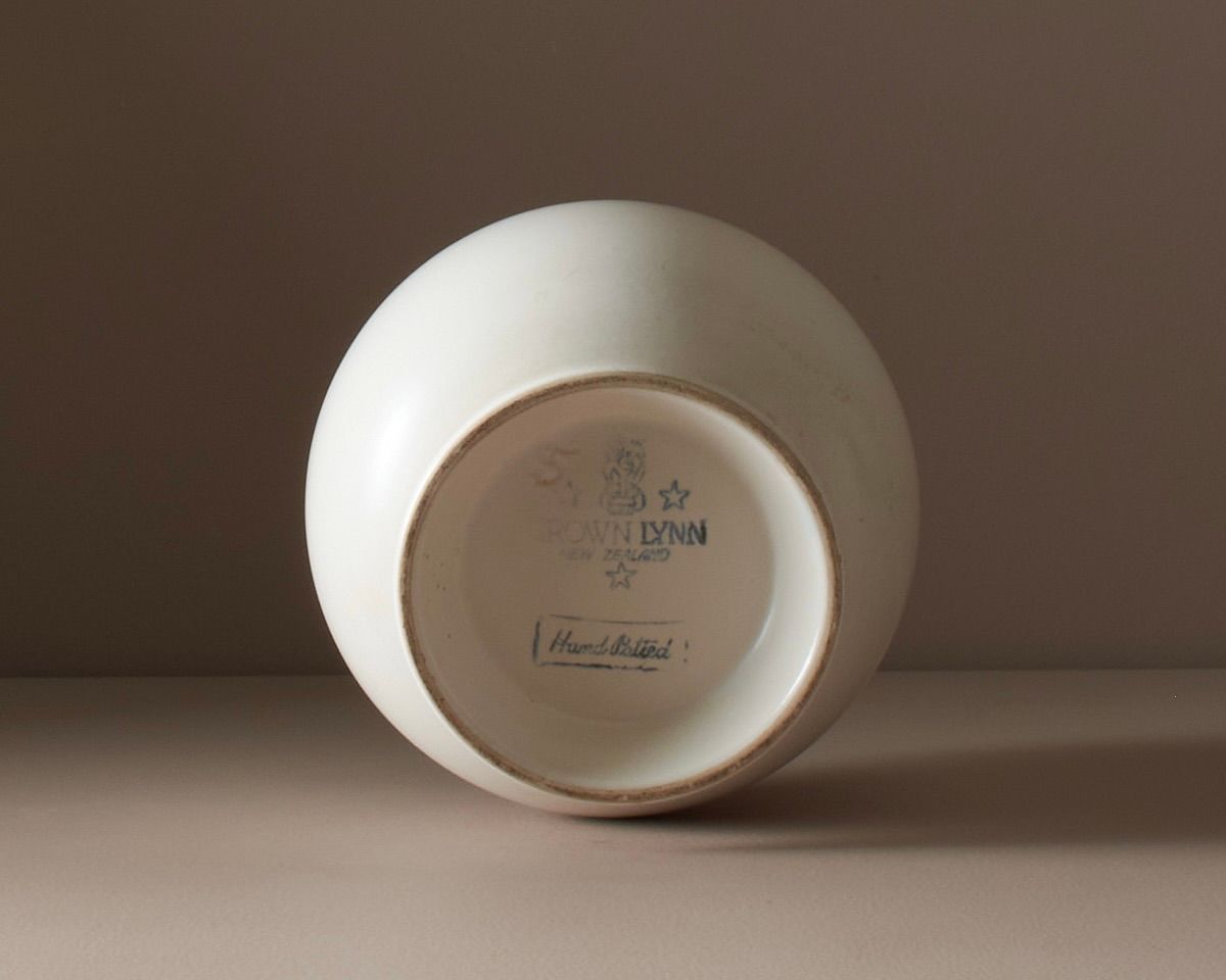 A detail photo of a Hand-potted vase Shape no.5 bearing a crown Lynn tiki stamp at the base.