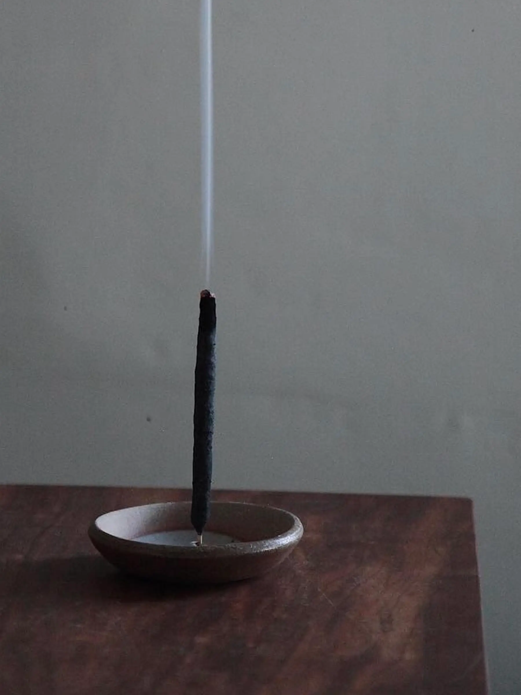 Incausa incense burning in a ceramic dish on a wooden surface