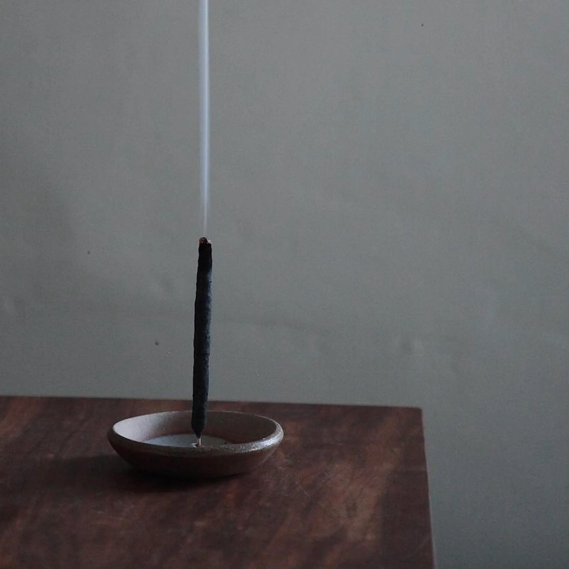 Incausa incense burning in a ceramic dish on a wooden surface