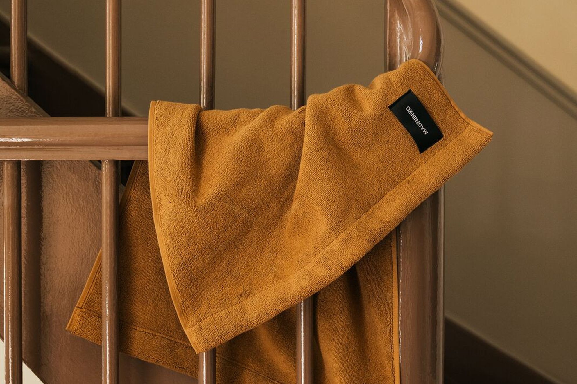 Magniberg Gelato hand towel in Nocciola beige, crafted from heavyweight 100% organic cotton terry and styled on a wooden staircase, available at Handcrafted Modern.