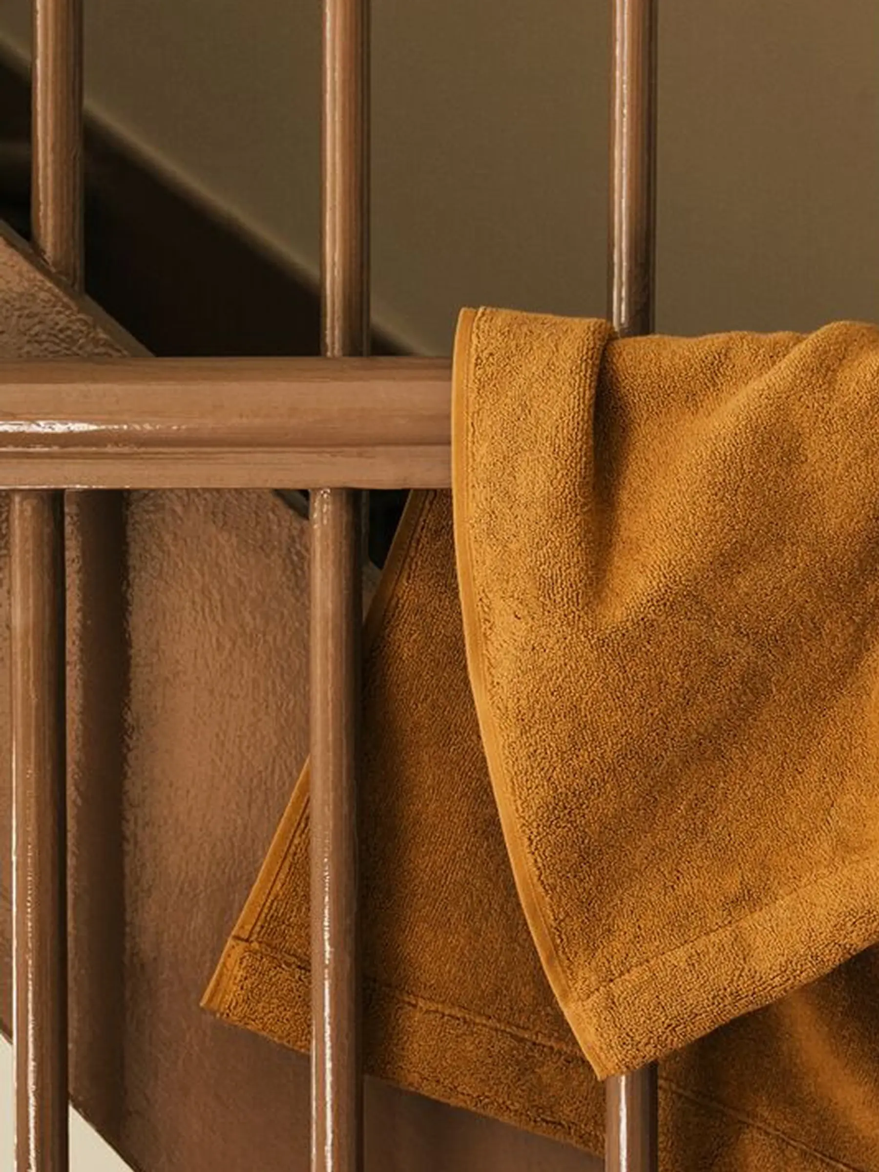 Magniberg Gelato hand towel in Nocciola beige, crafted from heavyweight 100% organic cotton terry and styled on a wooden staircase, available at Handcrafted Modern.