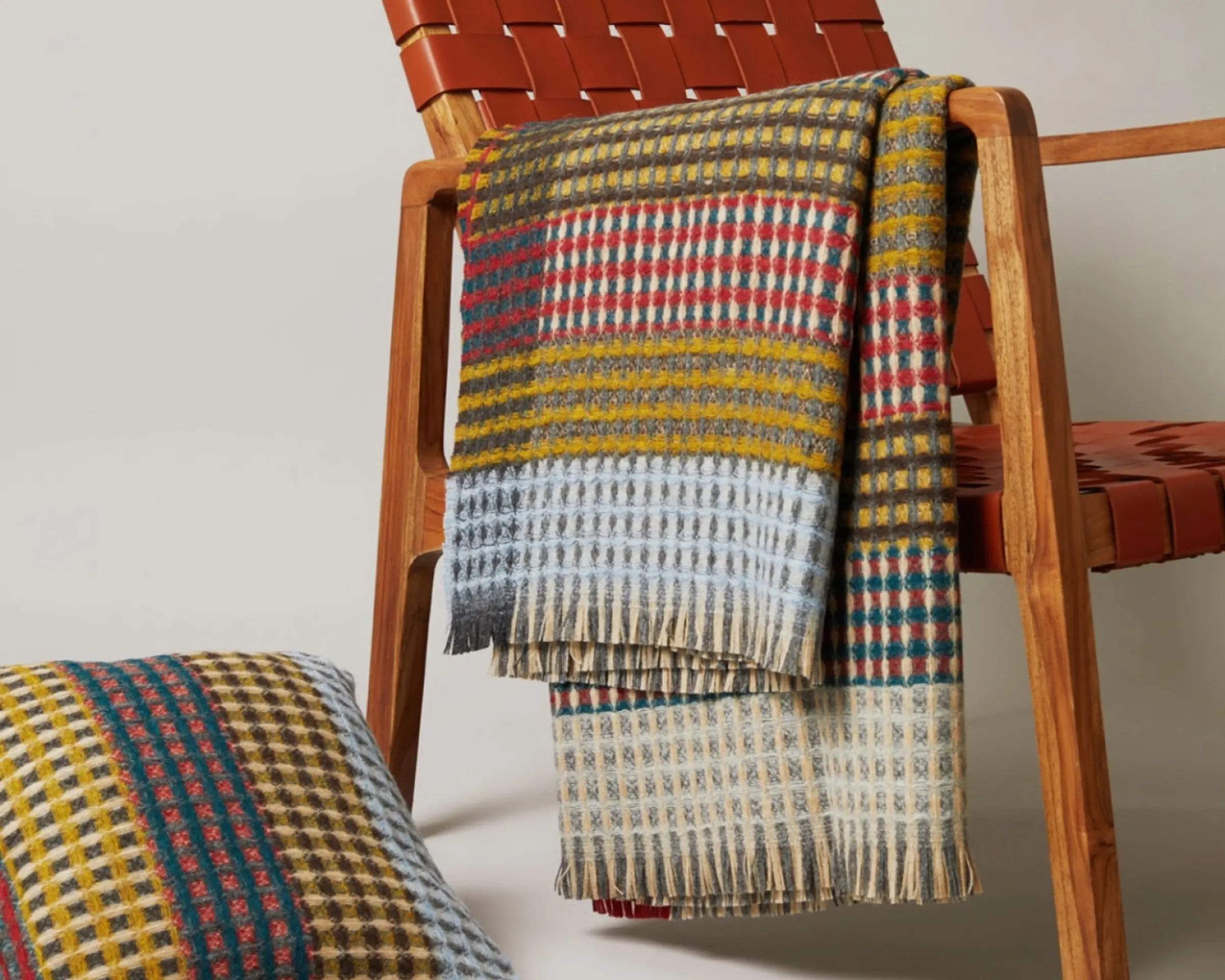 a wool blanket over the arm of a chair with the matching cushion