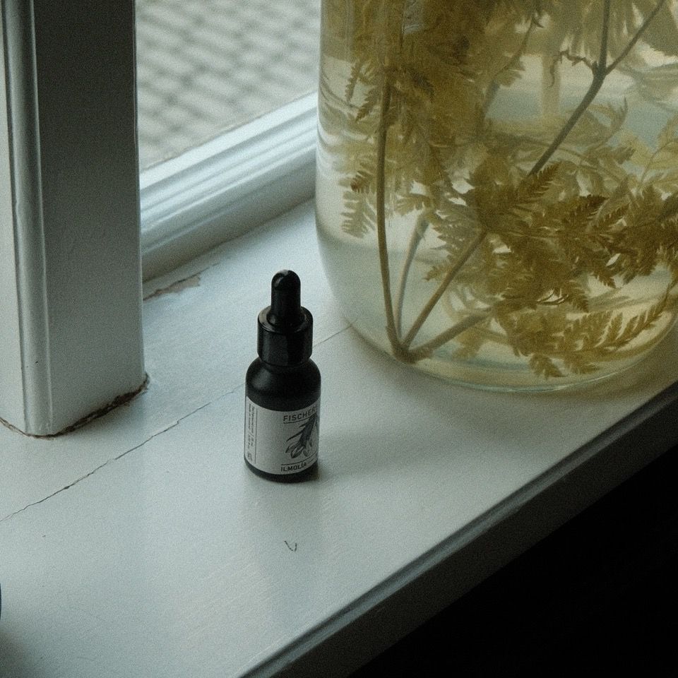 FISCHERSUND Perfume oil No. 23 on a windowsill near a jar containing water and fern fronds