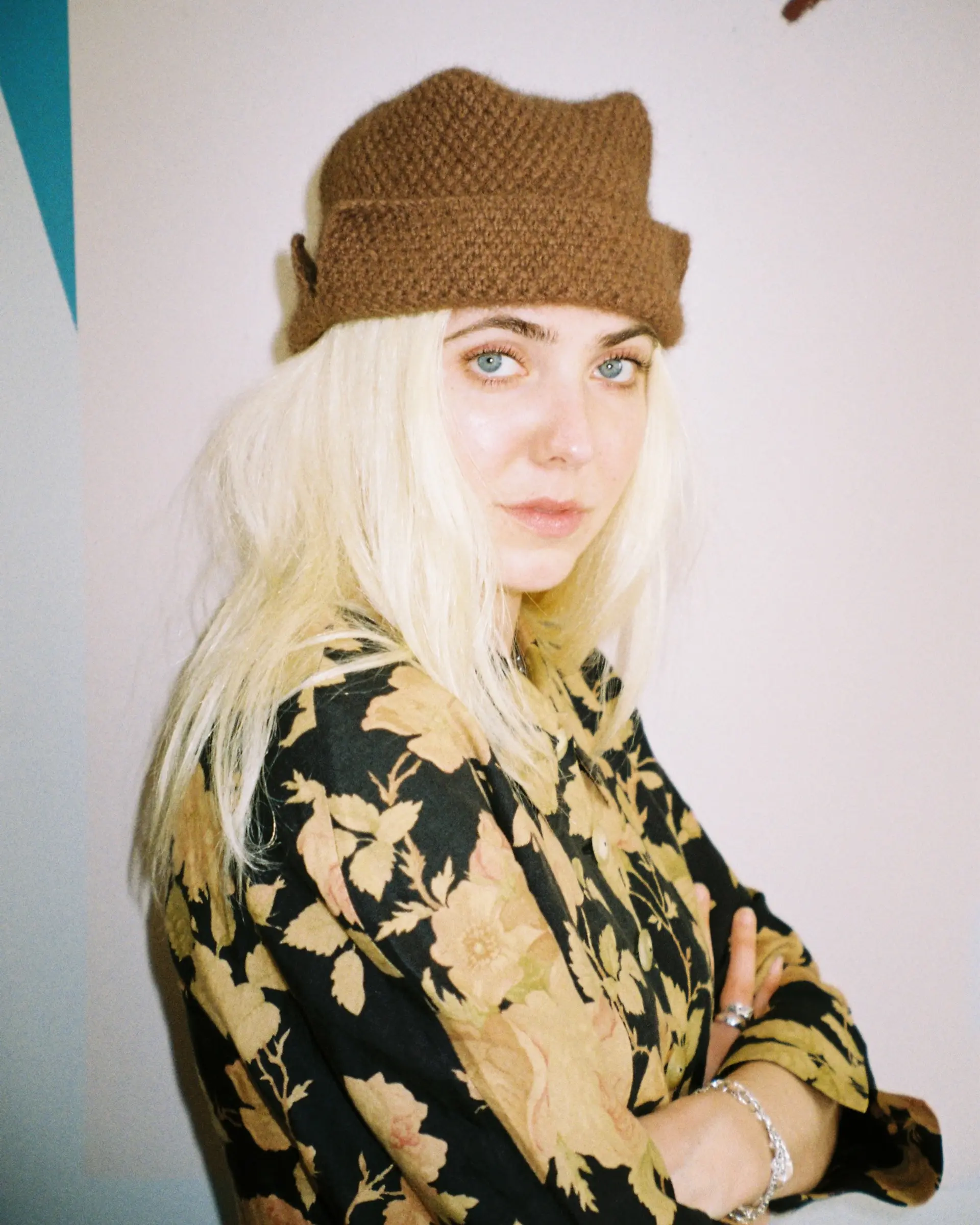 A woman wearing a Bonnie Wroe hand knit Ted hat made from a possum merino blend yarn, a square flat top shape. Well designed knitwear accessories made by hand