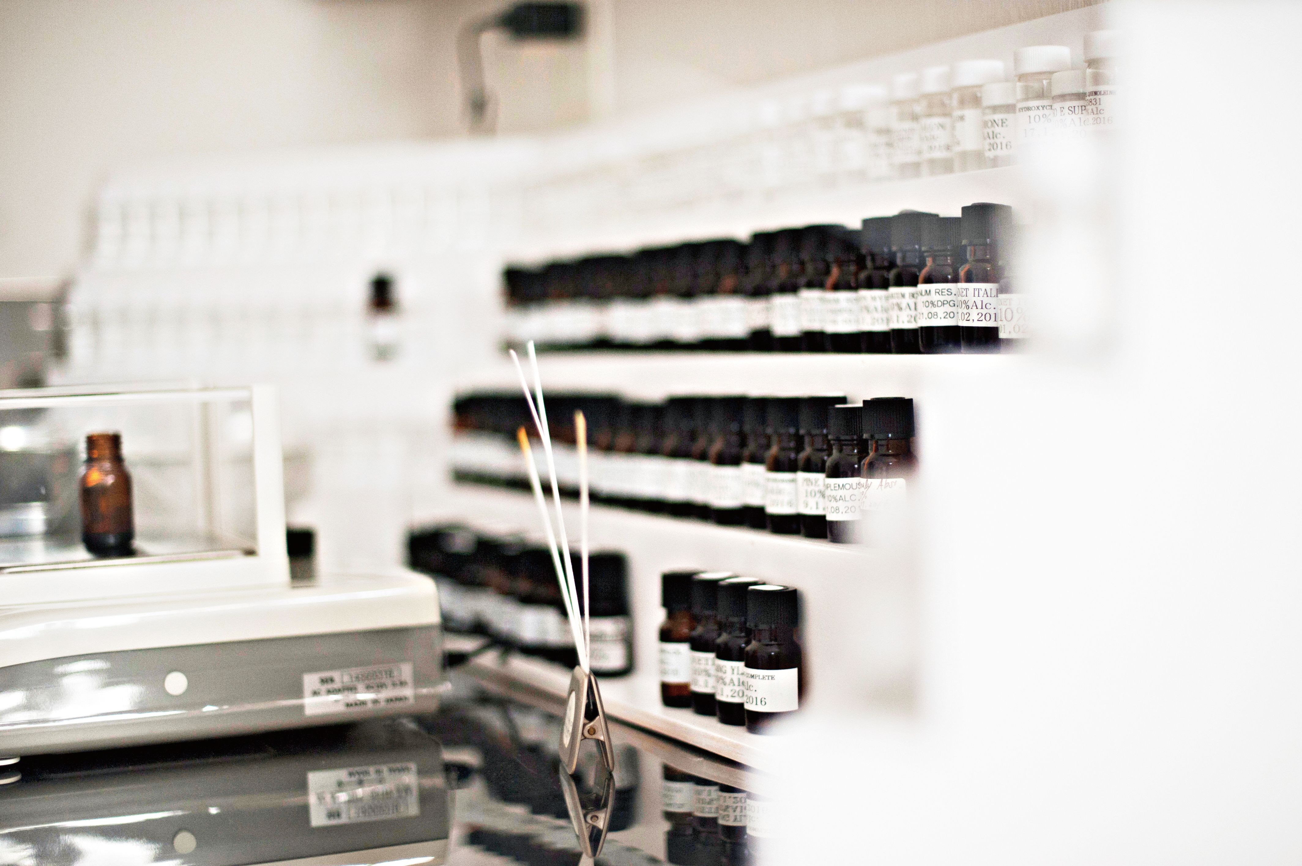 Small sample bottles of fragrance on a small white shelf with test strips infront of them
