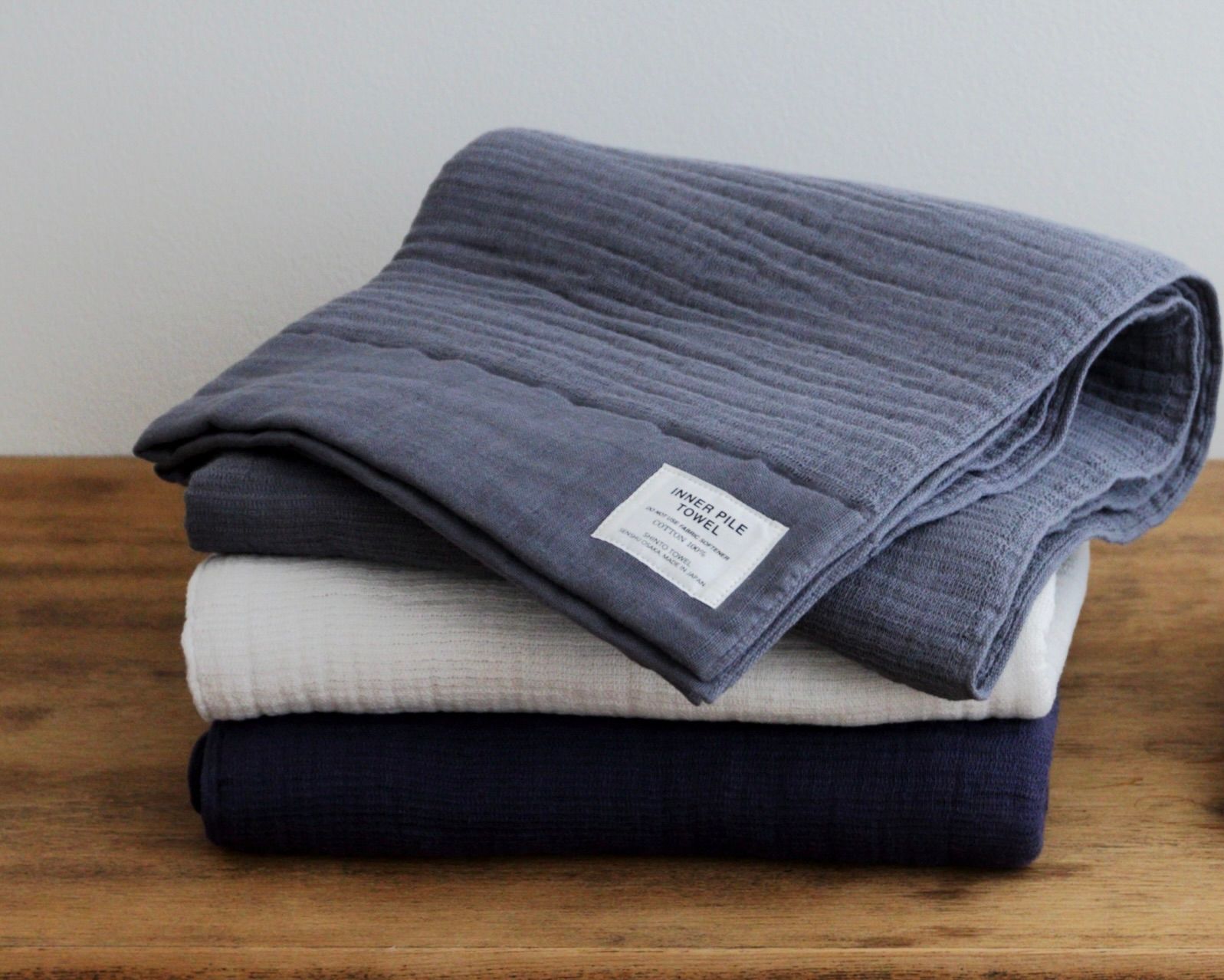 Three coloured Shinto bath towels folded on a wooden table