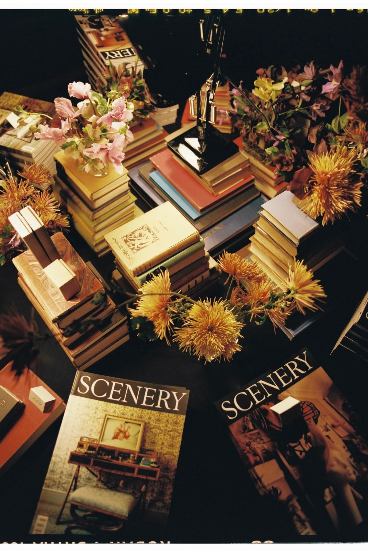 An image from Scenerys issue 4 launch with stacks of their magazines on a table with flowers and books beside them.