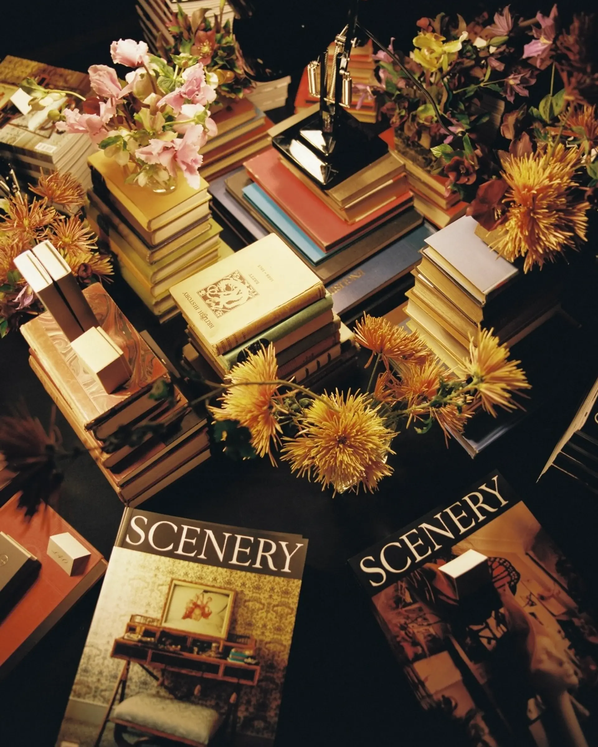 An image from Scenerys issue 4 launch with stacks of their magazines on a table with flowers and books beside them.