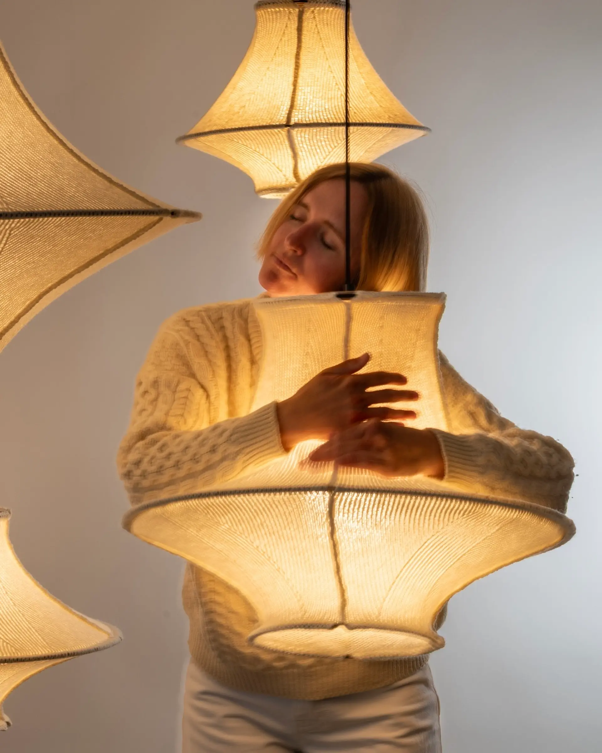 An image of Sophie Poelman the designer and owner of Lof Lighting hugging one of her Hiwa Wool light shades, made from 100% New Zealand strong wool