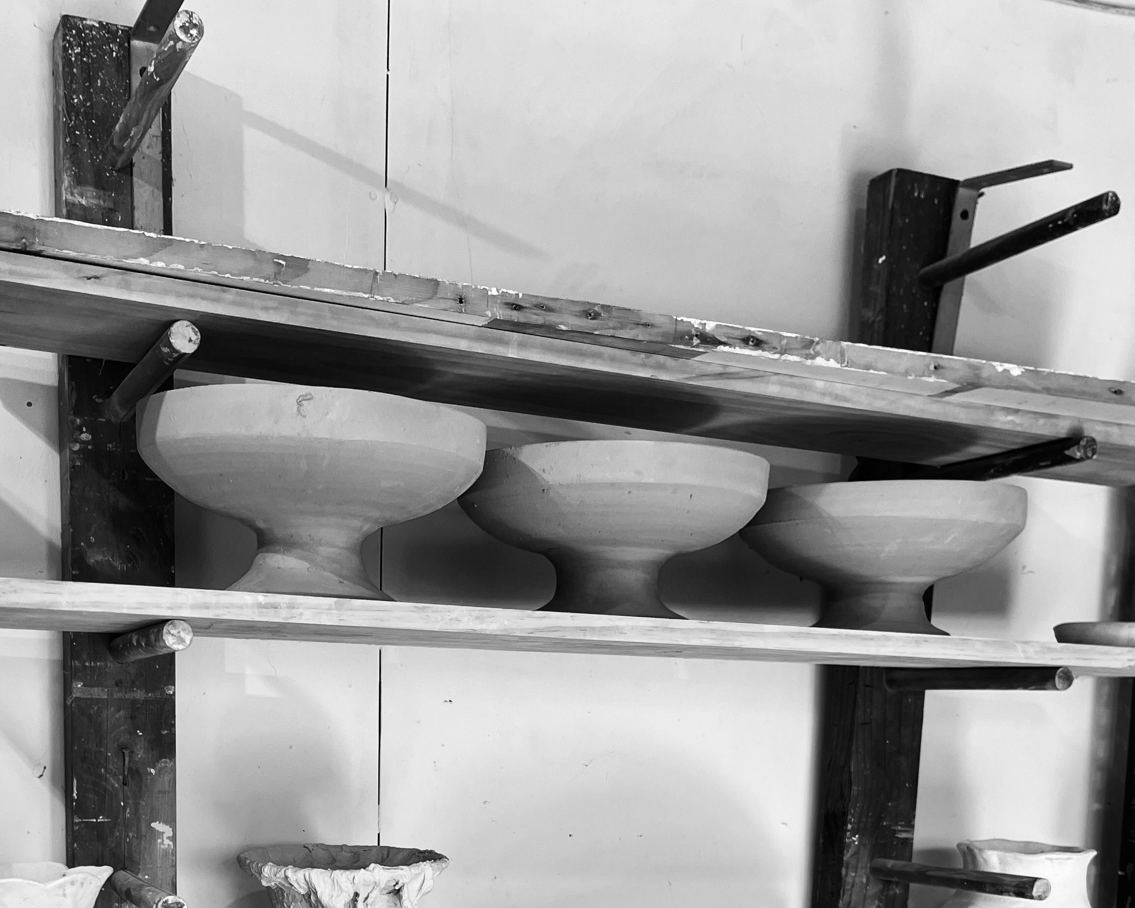 Kirsten dryburghs large stoneware footed bowls on a drying rack in her pottery studio