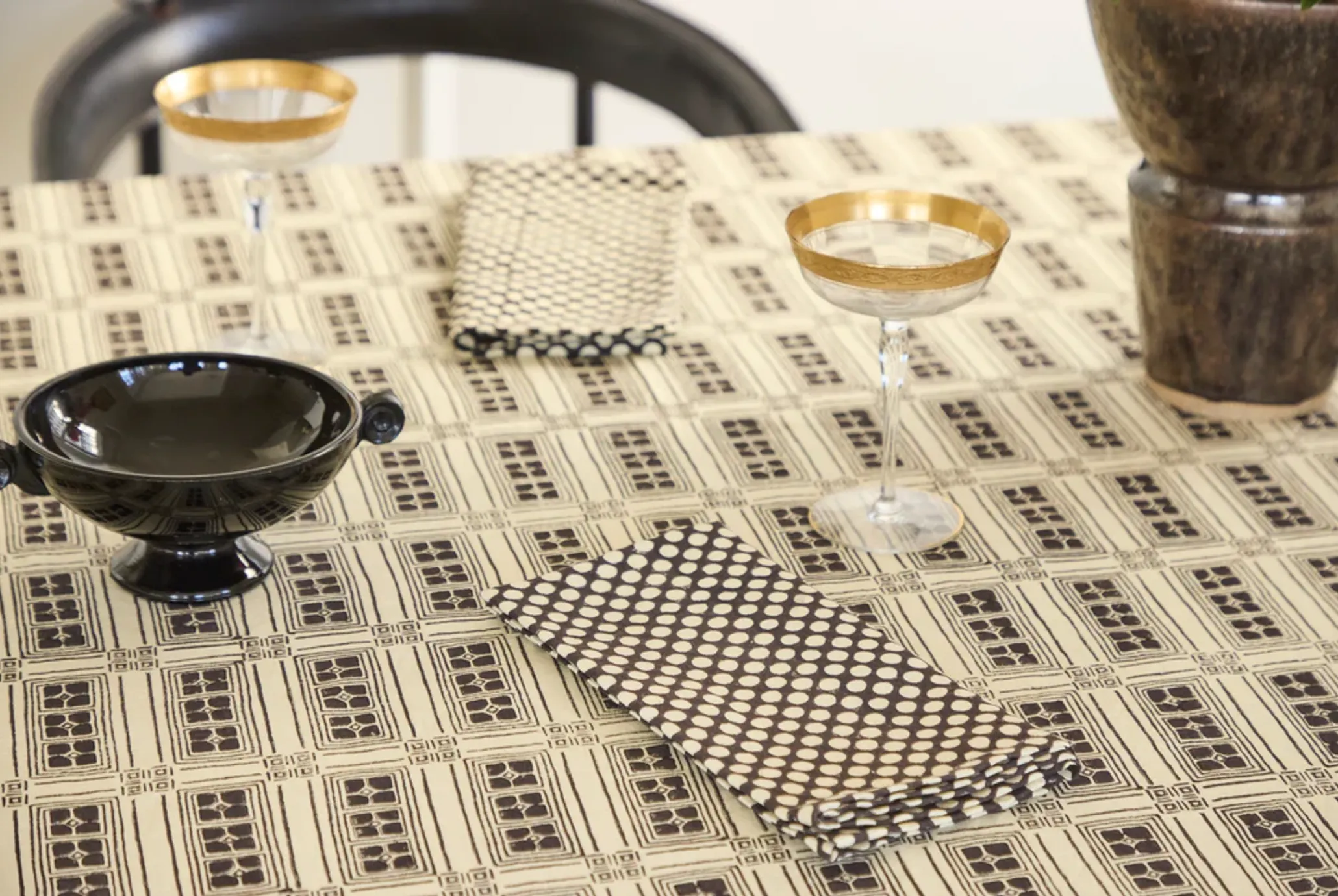 Vesuvius block printed napkins on a tabletop with vintage champagne glasses and ceramic dishes