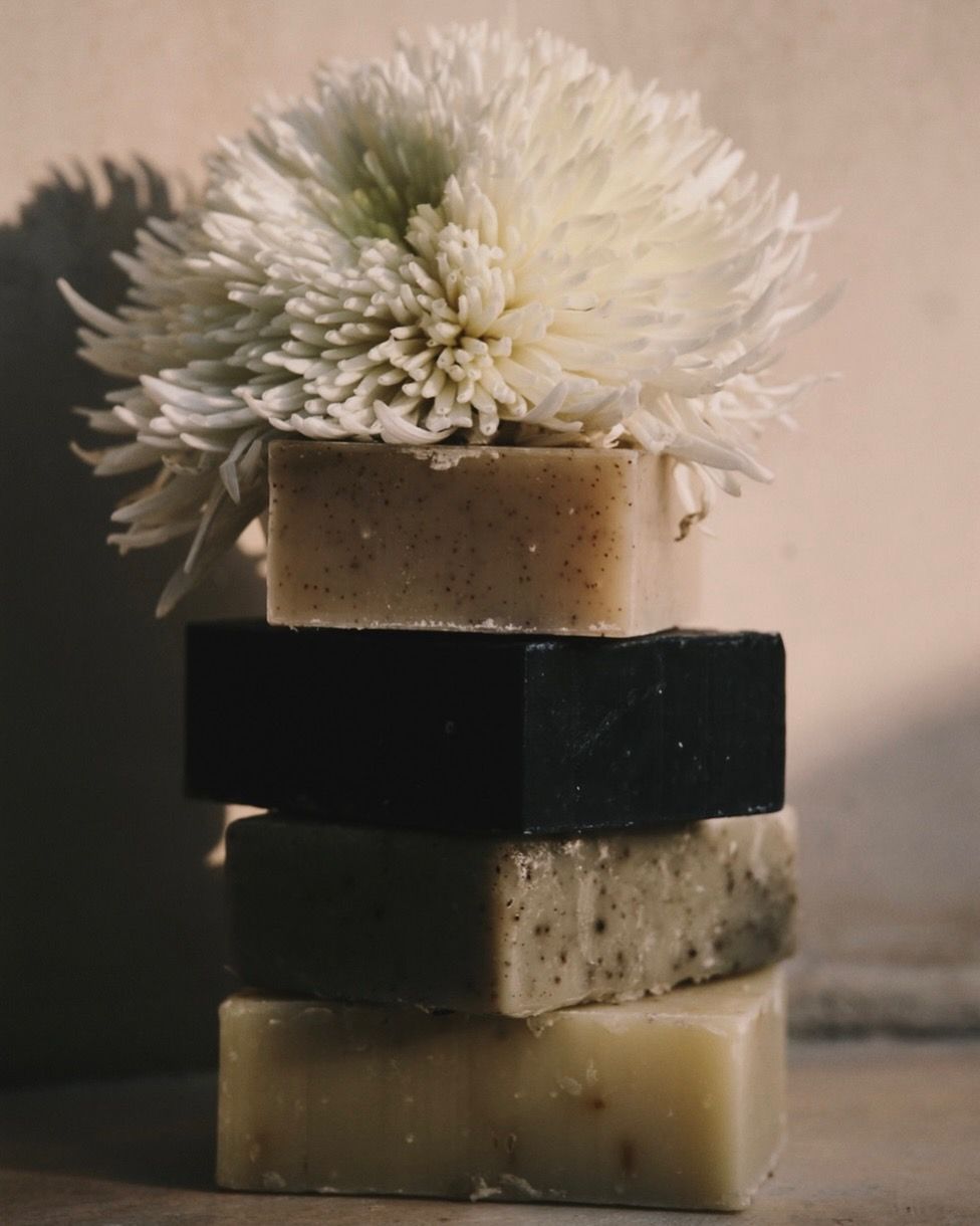 TU·ET·AL’s cold-pressed soaps stacked with a white Dahlia flower