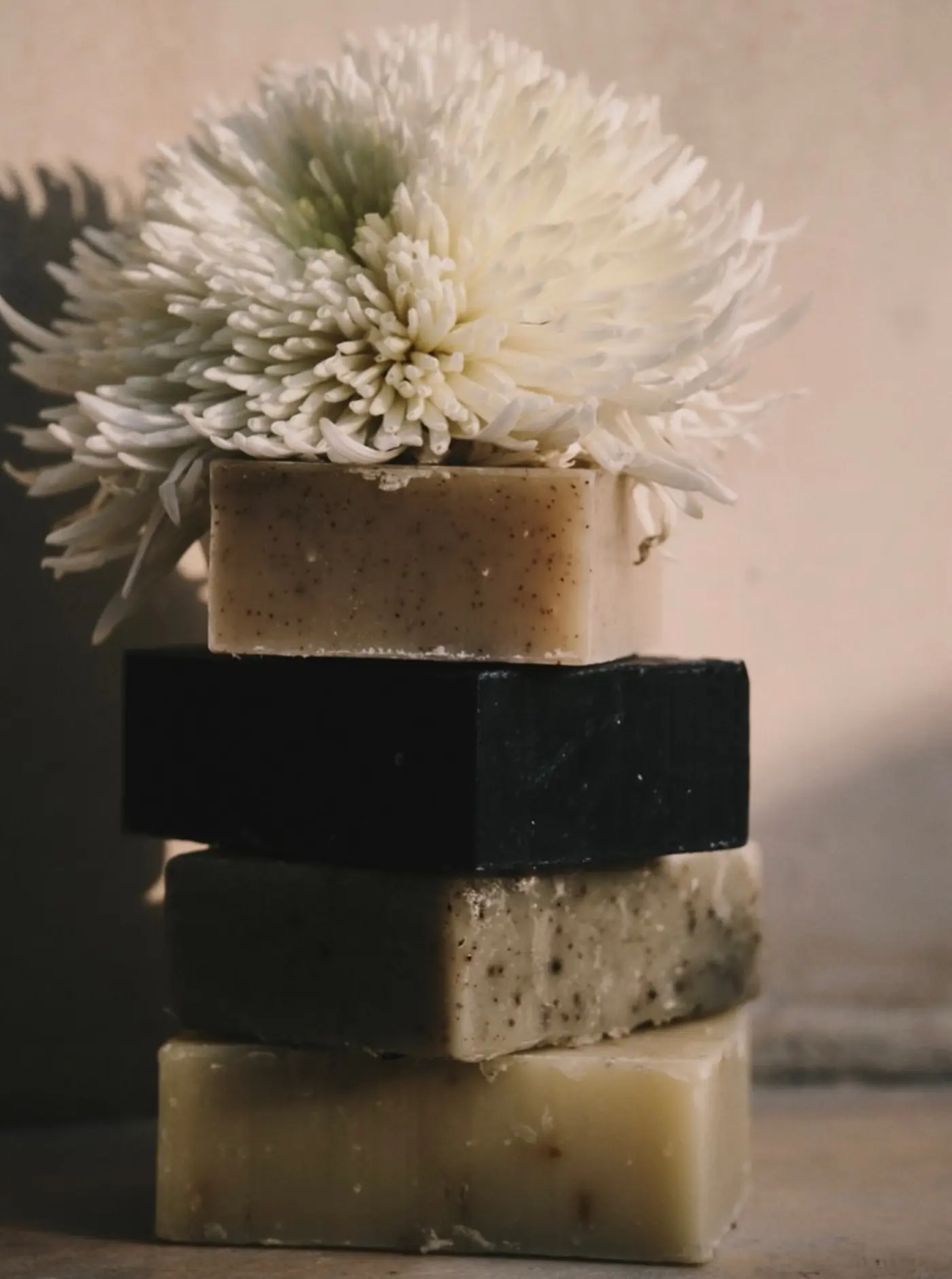 TU·ET·AL’s cold-pressed soaps stacked with a white Dahlia flower