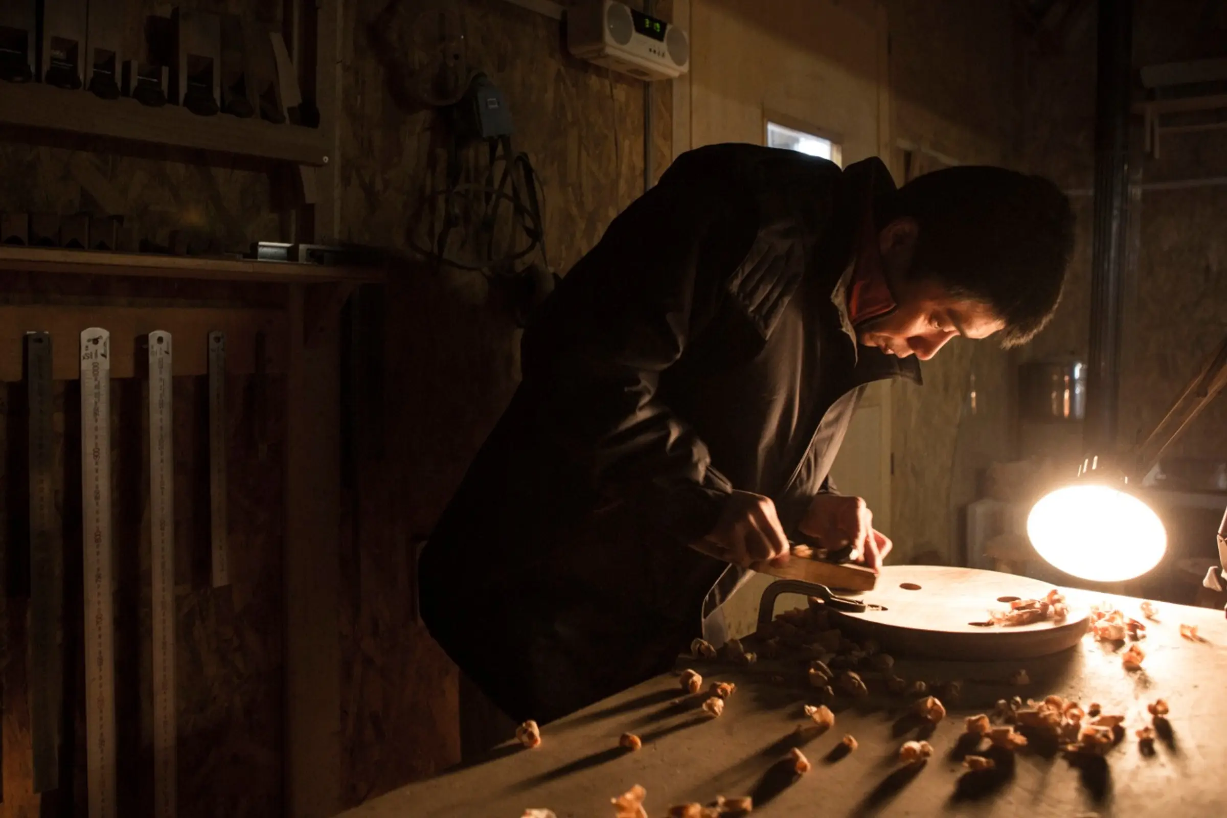 Iba hand carving the base of a stool in his workshop