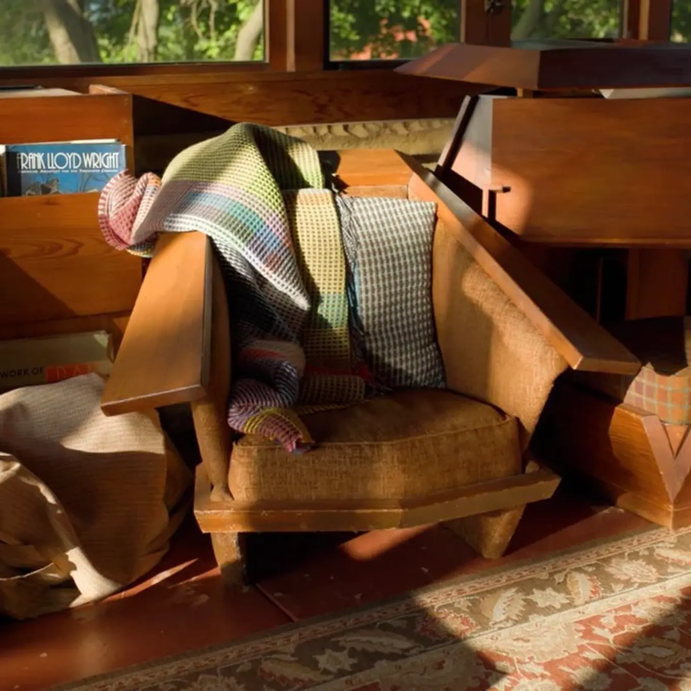 Wallace Sewell distinctive woven wool blankets, cushions, draped on a mid century modern wooden armchair in a Frank Lloyd Wright designed house.