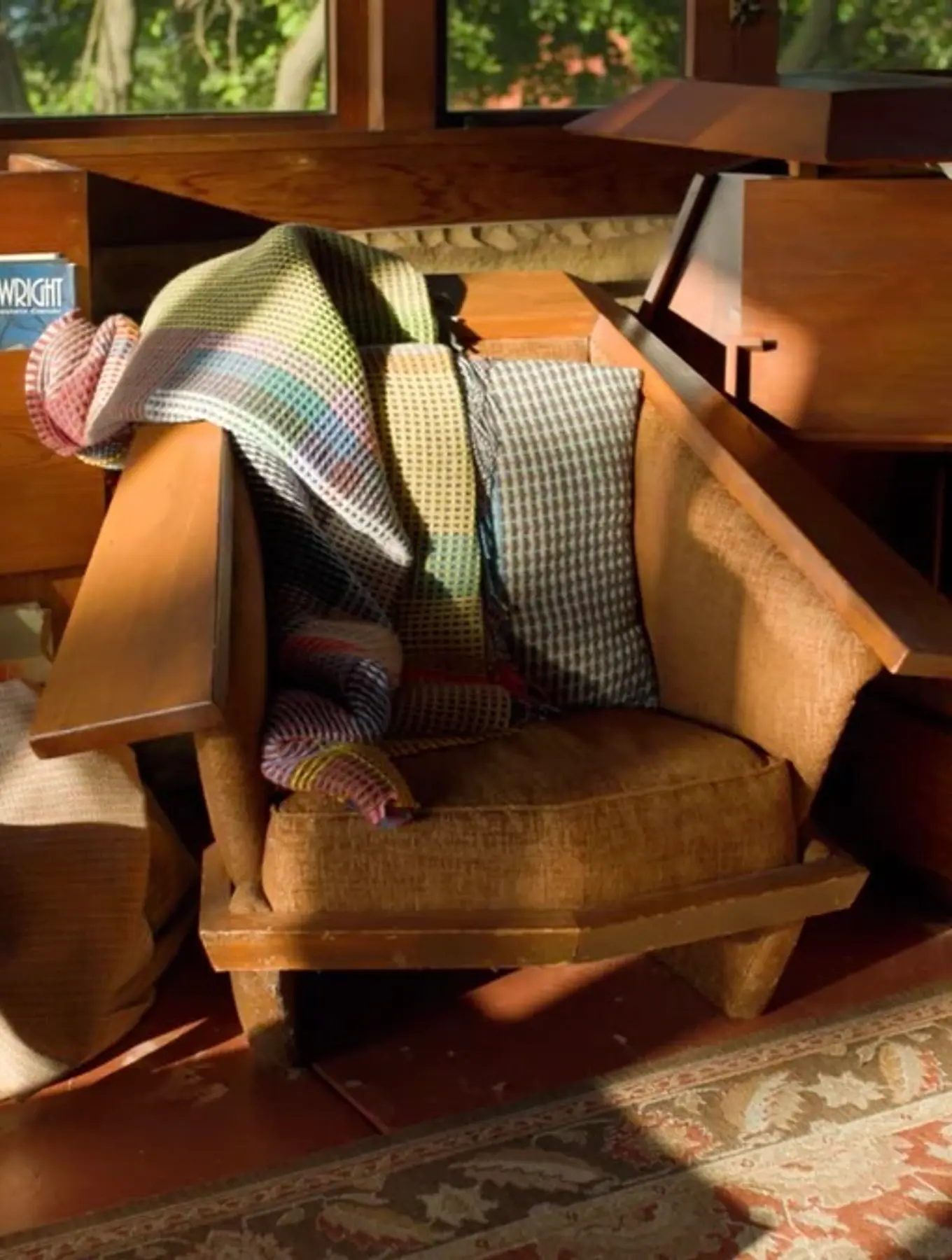 Wallace Sewell distinctive woven wool blankets, cushions, draped on a mid century modern wooden armchair in a Frank Lloyd Wright designed house.