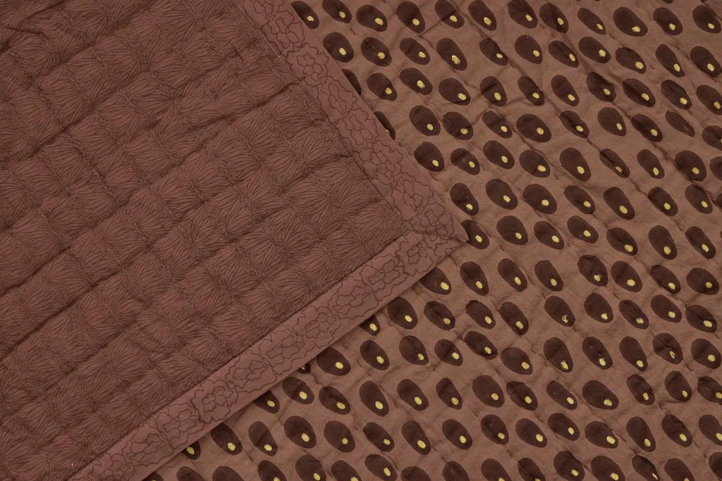 A close up of the Studio ford sphinx reversible quilt in warm brown tones